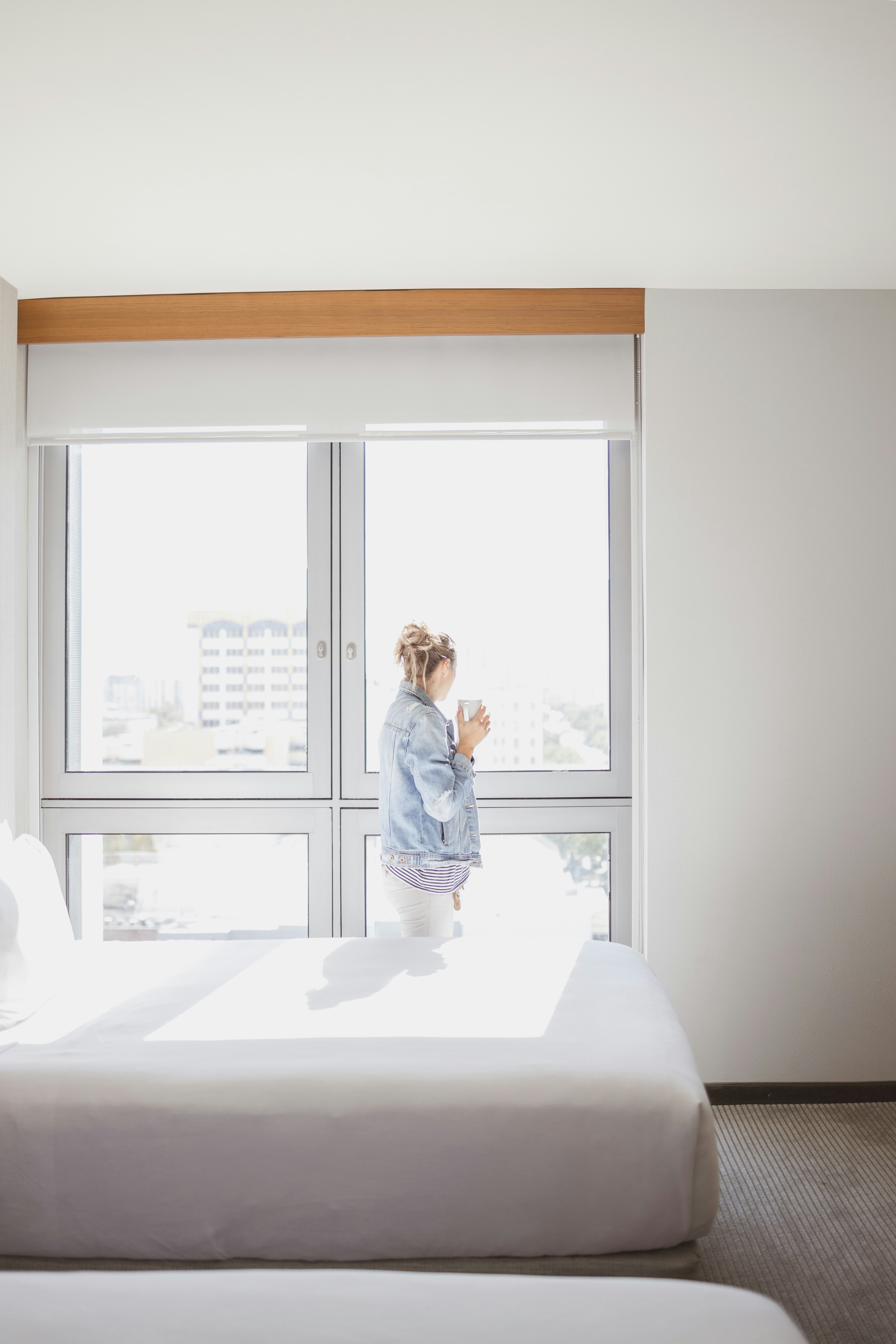 woman watching on glass window near empty bed