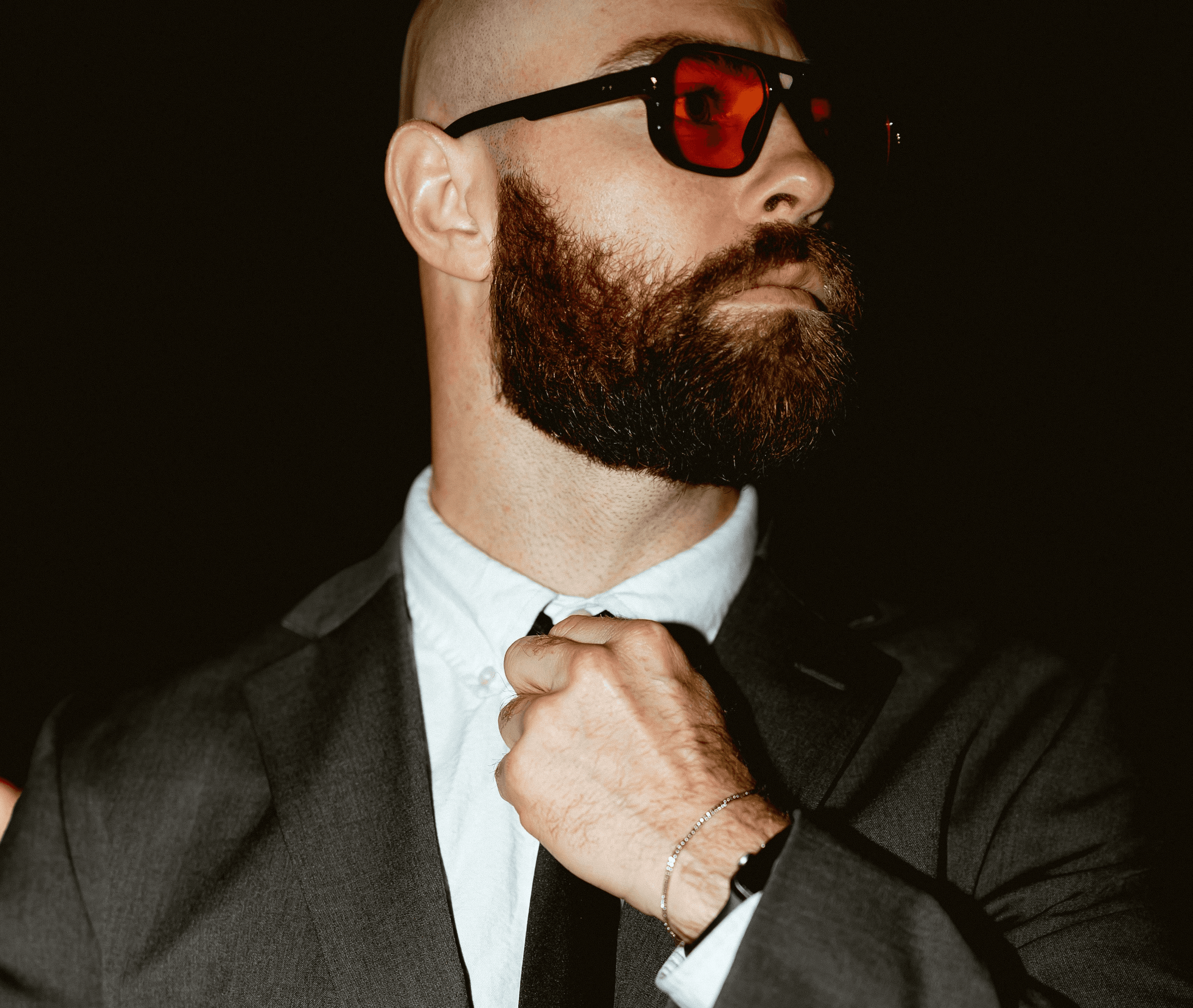 Man in suit adjusting his tie at night