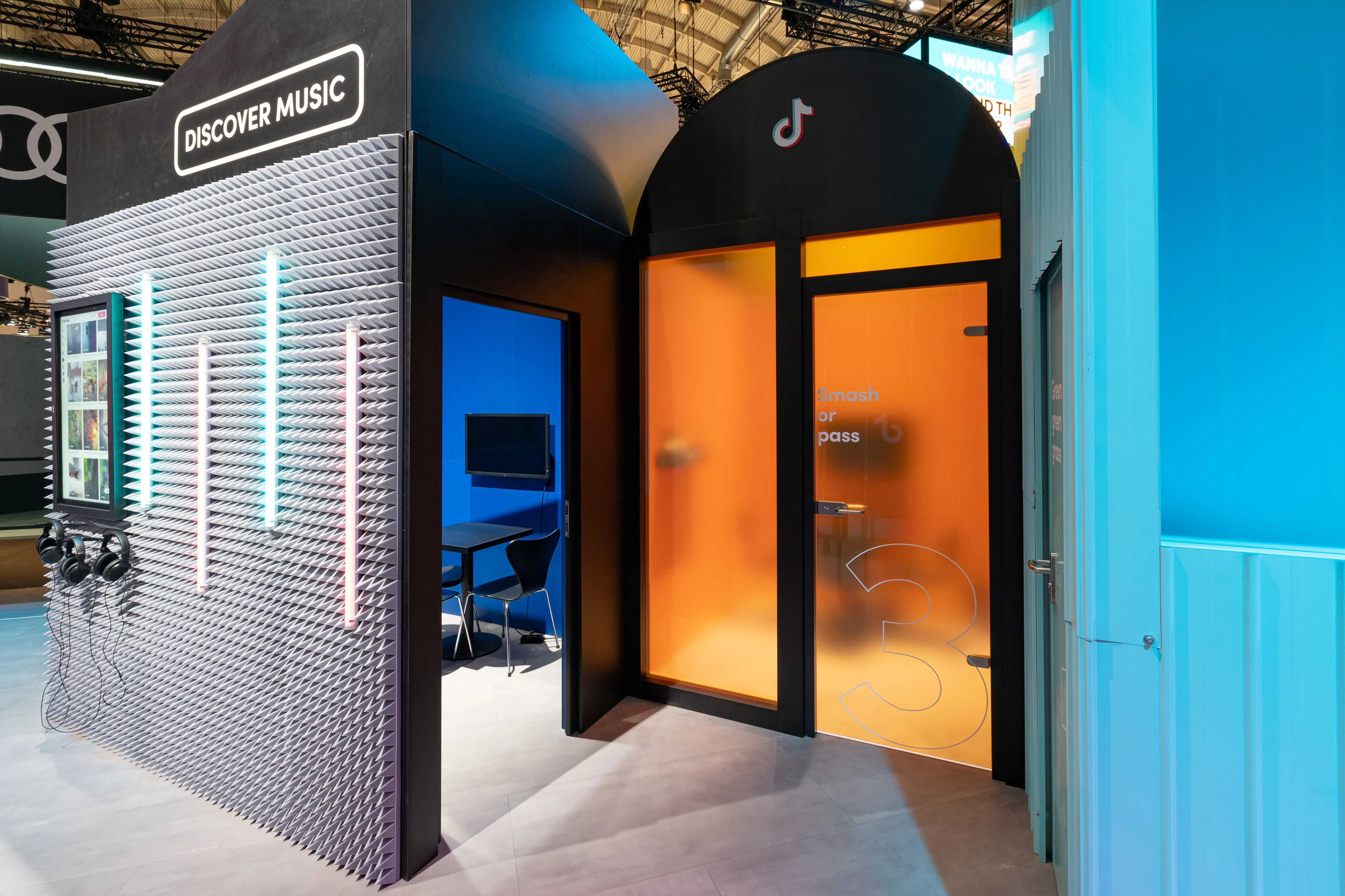 Discover Music box with grey foam facade, headphones and neon tubes next to an orange Smash or Pass door at the TikTok booth.
