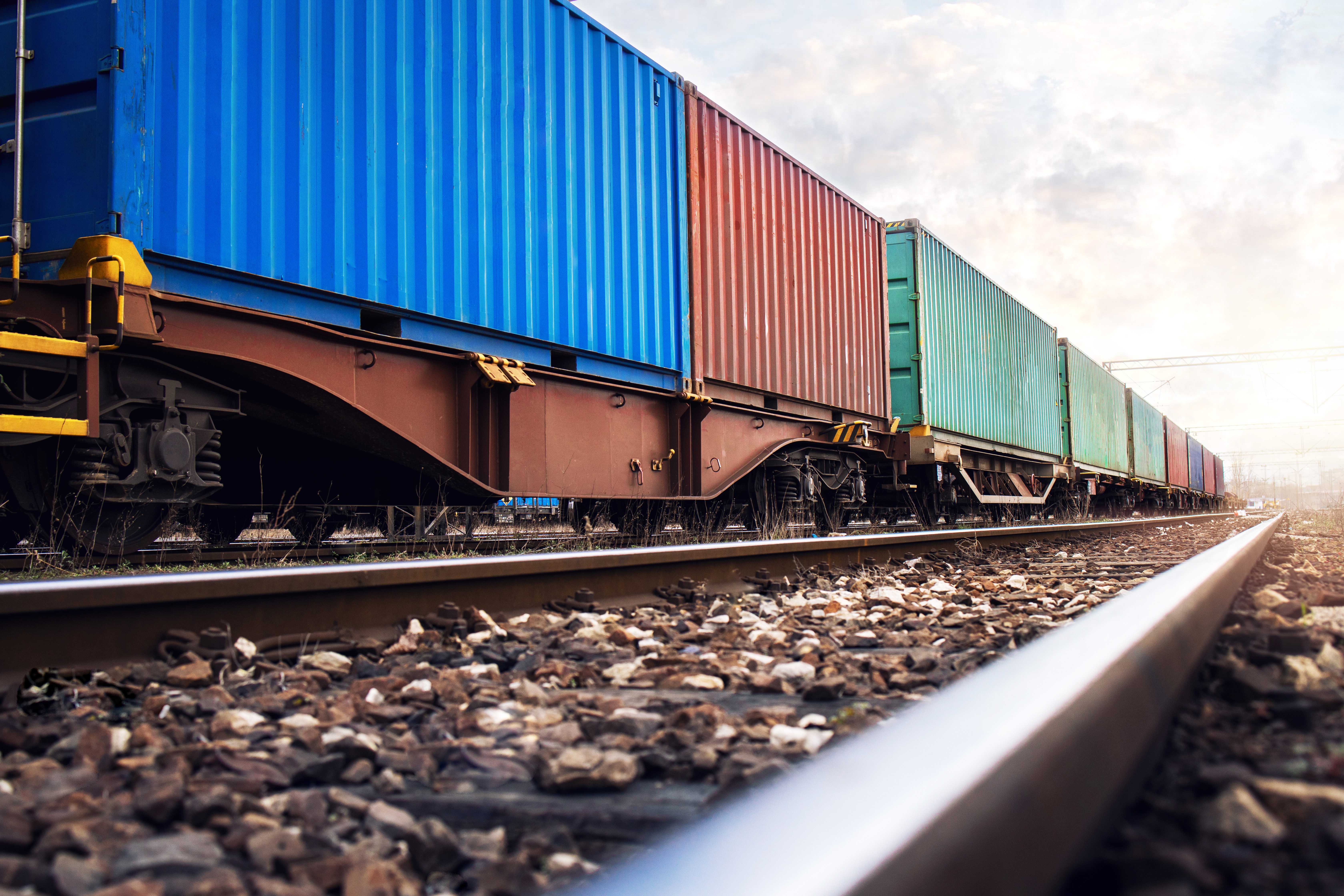 Train de marchandises transportant des conteneurs colorés sur une voie ferrée.