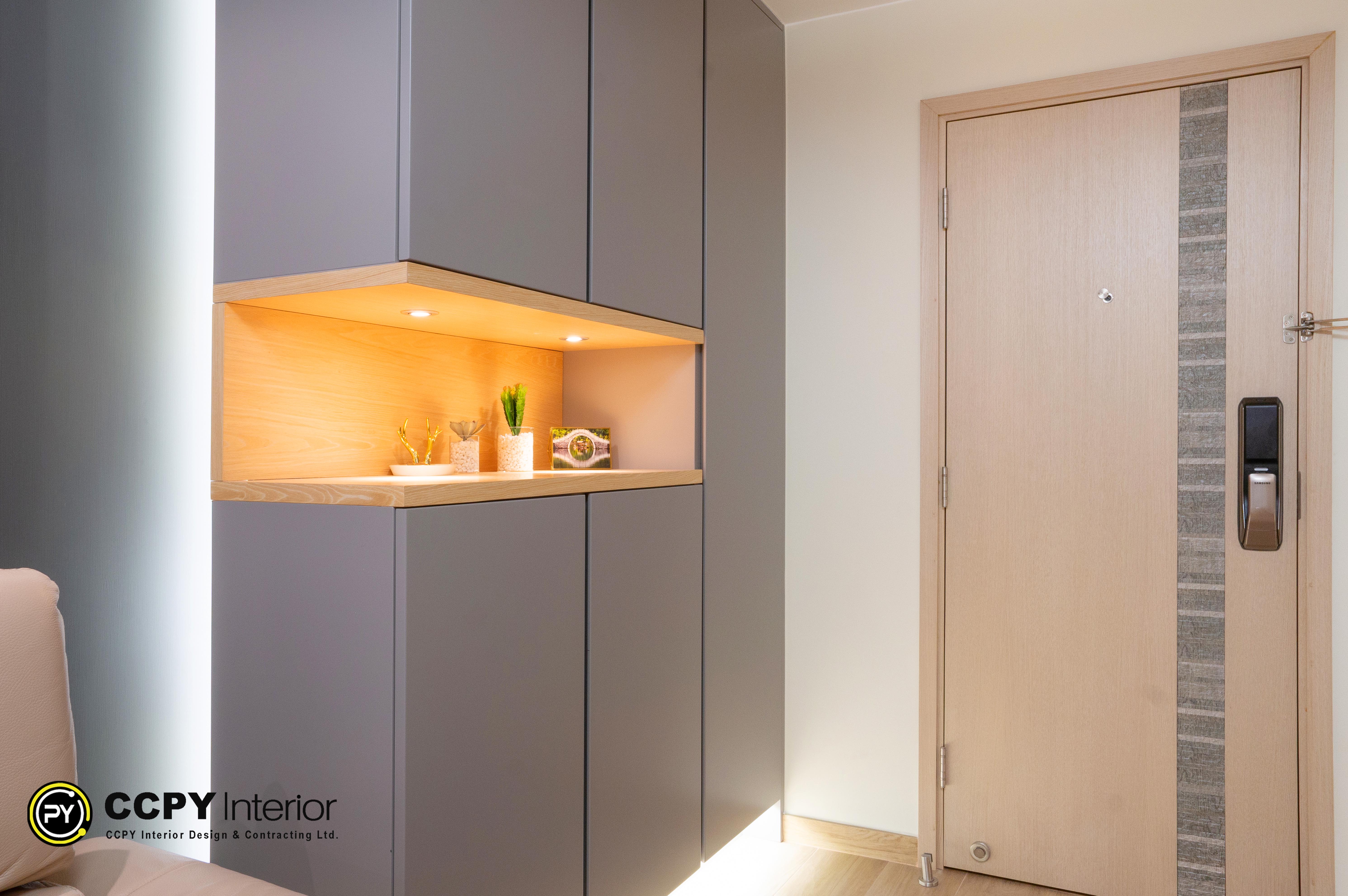 The selected region shows a modern entry foyer featuring a custom-built, multi-functional storage cabinet next to an apartment front door.Design BreakdownSmart Zoning: The tall, grey cabinet unit acts as both a shoe organizer and a subtle room divider between the entryway and the main living space.Warm Open Niche: A central cutout features a warm wood finish and integrated LED downlighting, creating an inviting display area for keys, decor, or small plants.Streamlined Entryway: The wooden main door is equipped with a modern electronic smart lock, complementing the sleek, handleless aesthetic of the custom cabinetry.