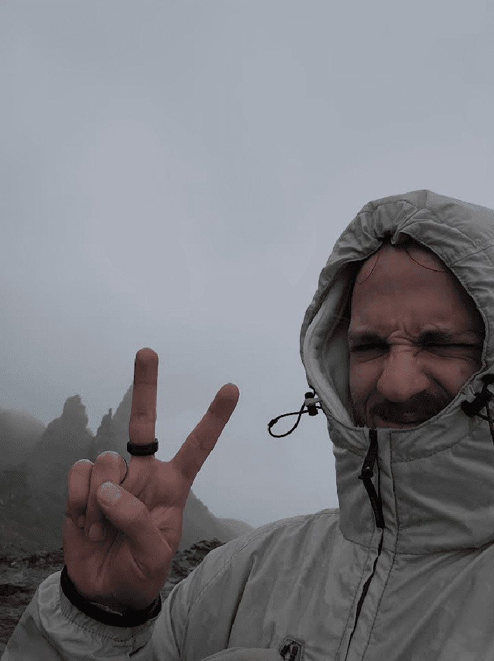 A selfie of me (Axel Dufour) taking a picture at the very top ofa mountain, yet smiling and making a peace sign ✌️.