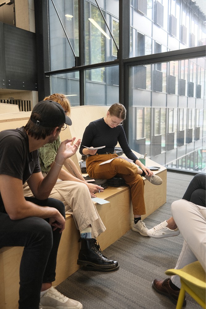 Kolleg:innen sitzen auf Stufen und besprechen ein Projekt.