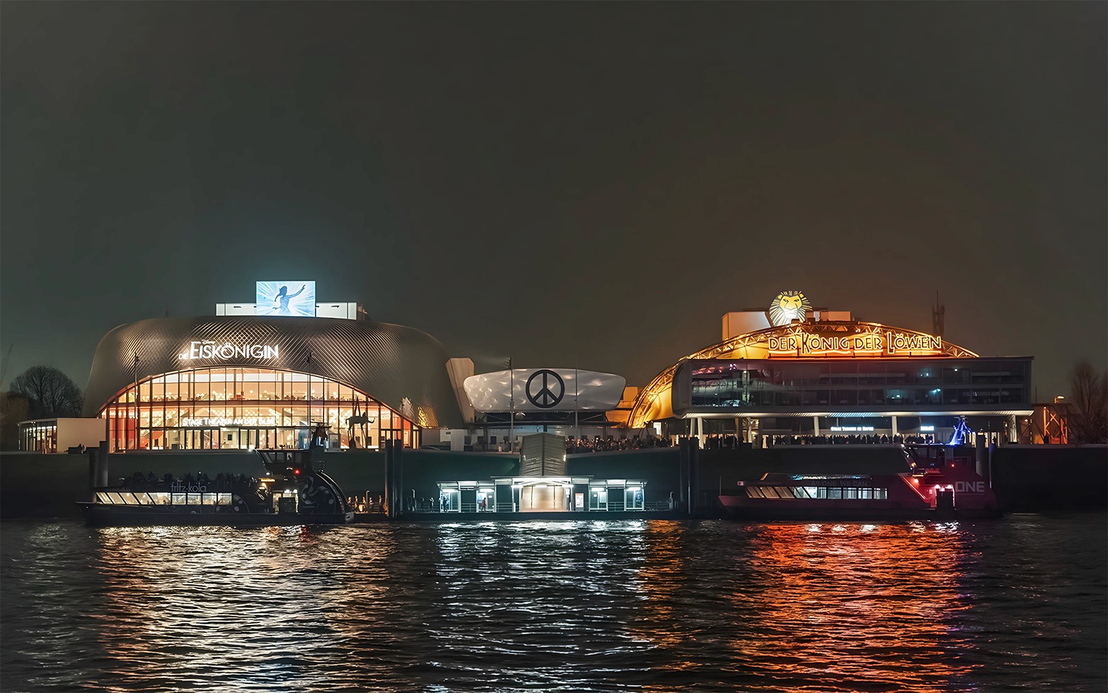 大港湾夜景，灯火辉煌的剧院倒映在水面上。