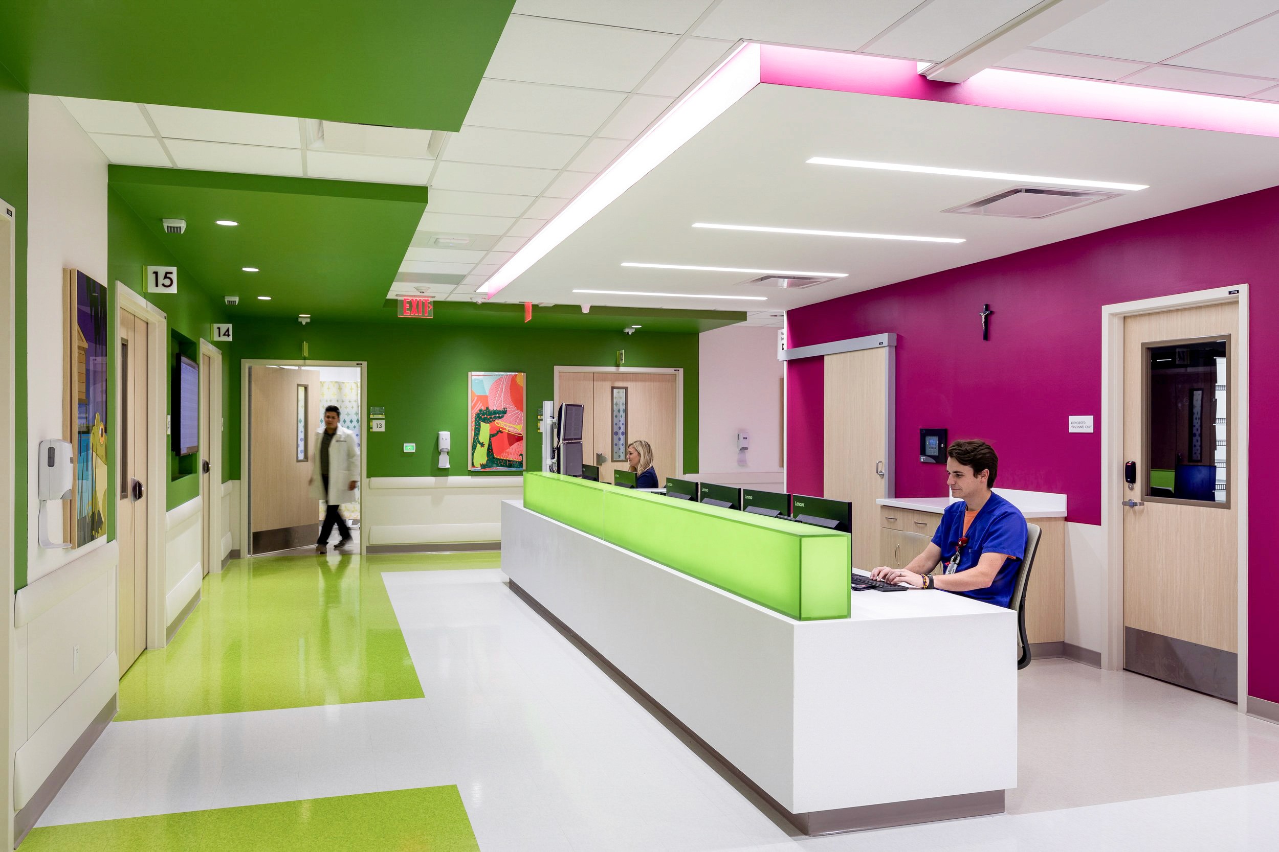 Modern hospital reception area with green and pink walls.