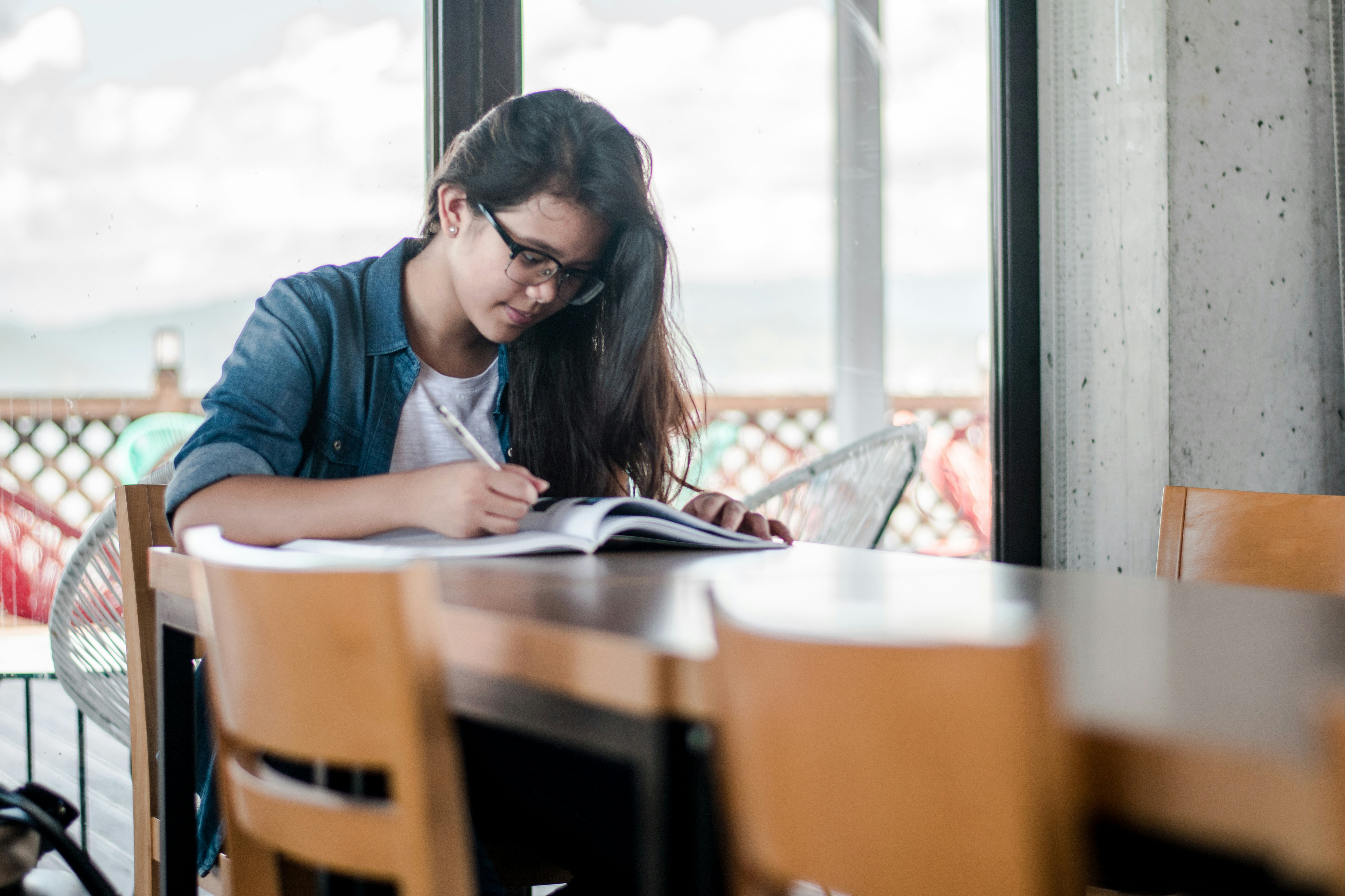 girl sitting on a chair and writing on a copy - ai for academic writing