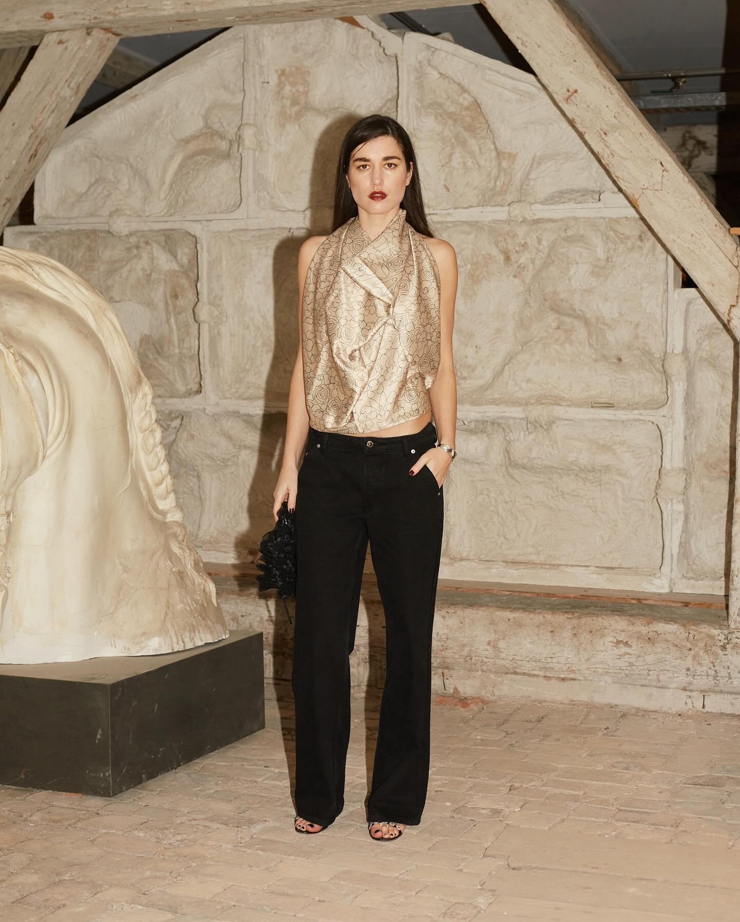 Une mannequin au défilé Operasport porte un top beige brillant et un pantalon noir