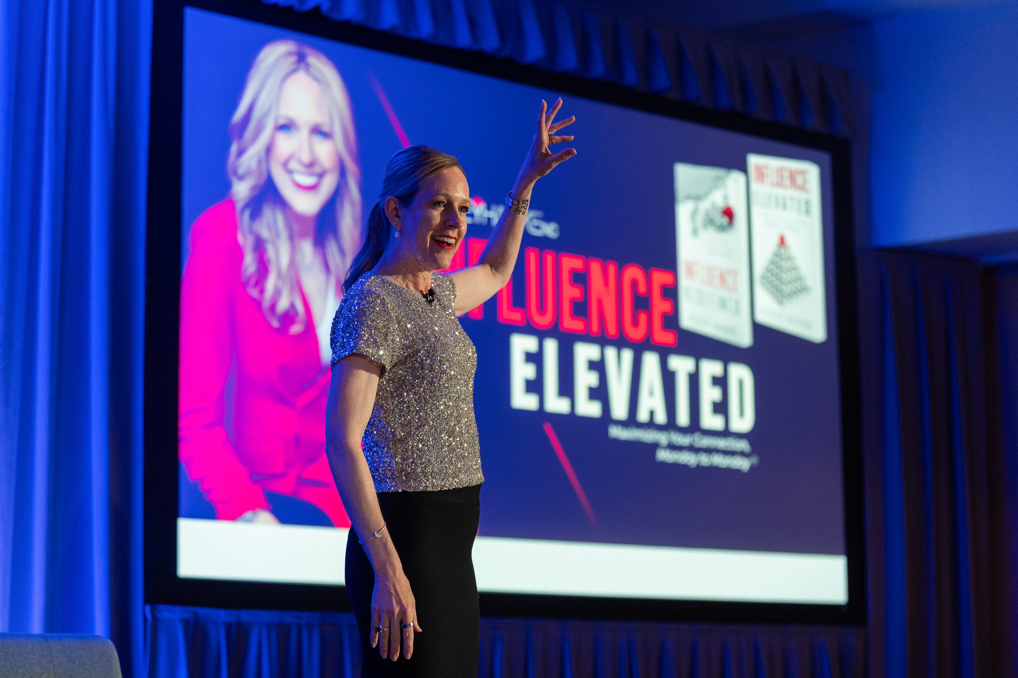 Stacey Hanke, keynote speaker, standing on stage delivering Influence Elevated to an audience.