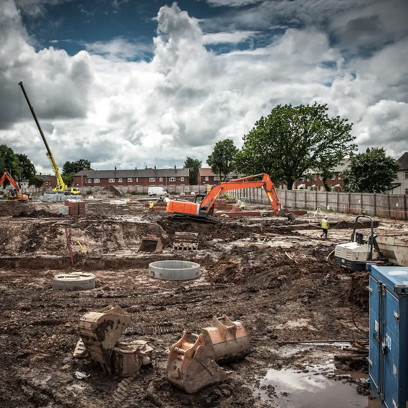 Excavators and groundworks equipment preparing a commercial land development site with drainage installation and foundation works in progress.