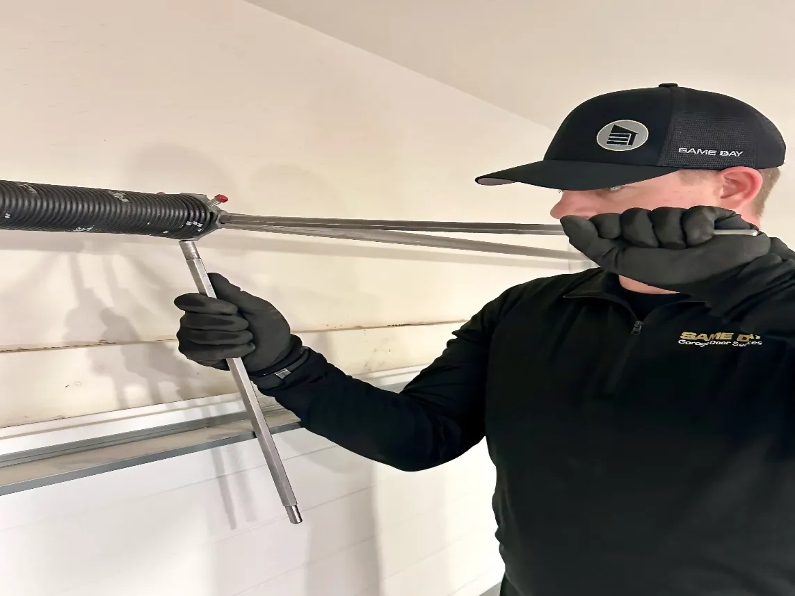 same day garage door services technician tighting a spring on a garage door repair job
