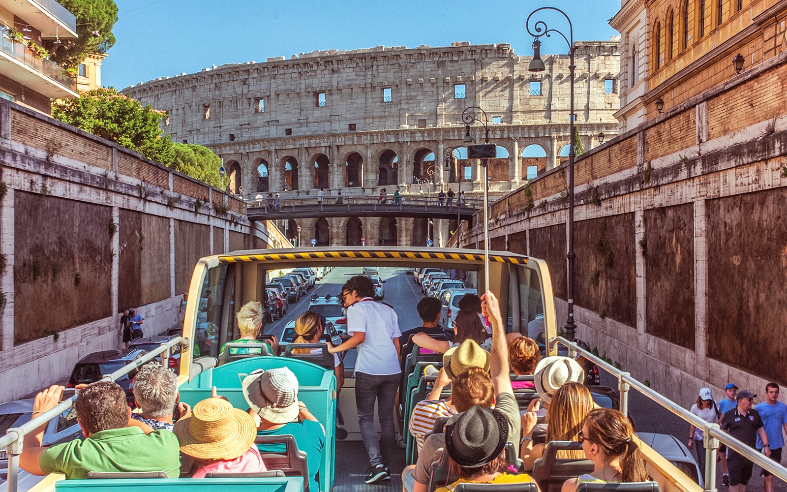 Tour guide interacting with tourists on a bus near the Colosseum in Rome.