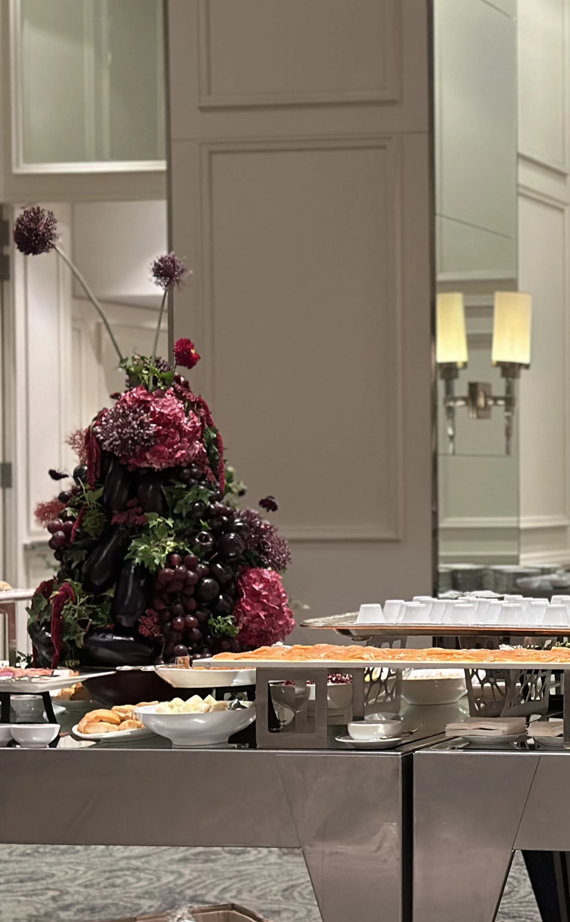 Perspectiva de buffet de lujo con centro de mesa barroco inmersivo, bandejas de salmón y mesas espejadas.