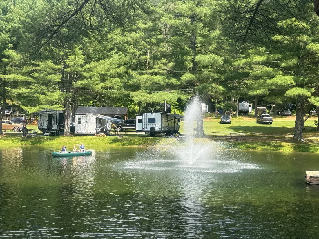 RV park in Pownal, Vermont, with campers parked along a scenic pond and tall evergreen trees.