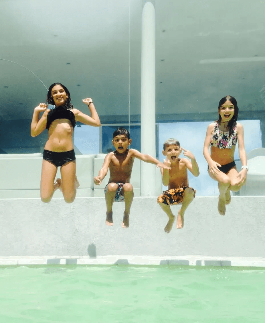 Niños felices saltando a una piscina con revestimiento Aquavations, color aqua.