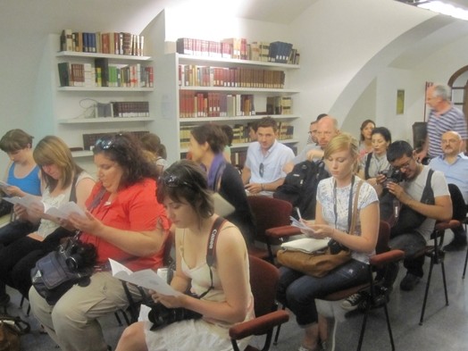 A group of people sitting in a classroom and reading some flyers.