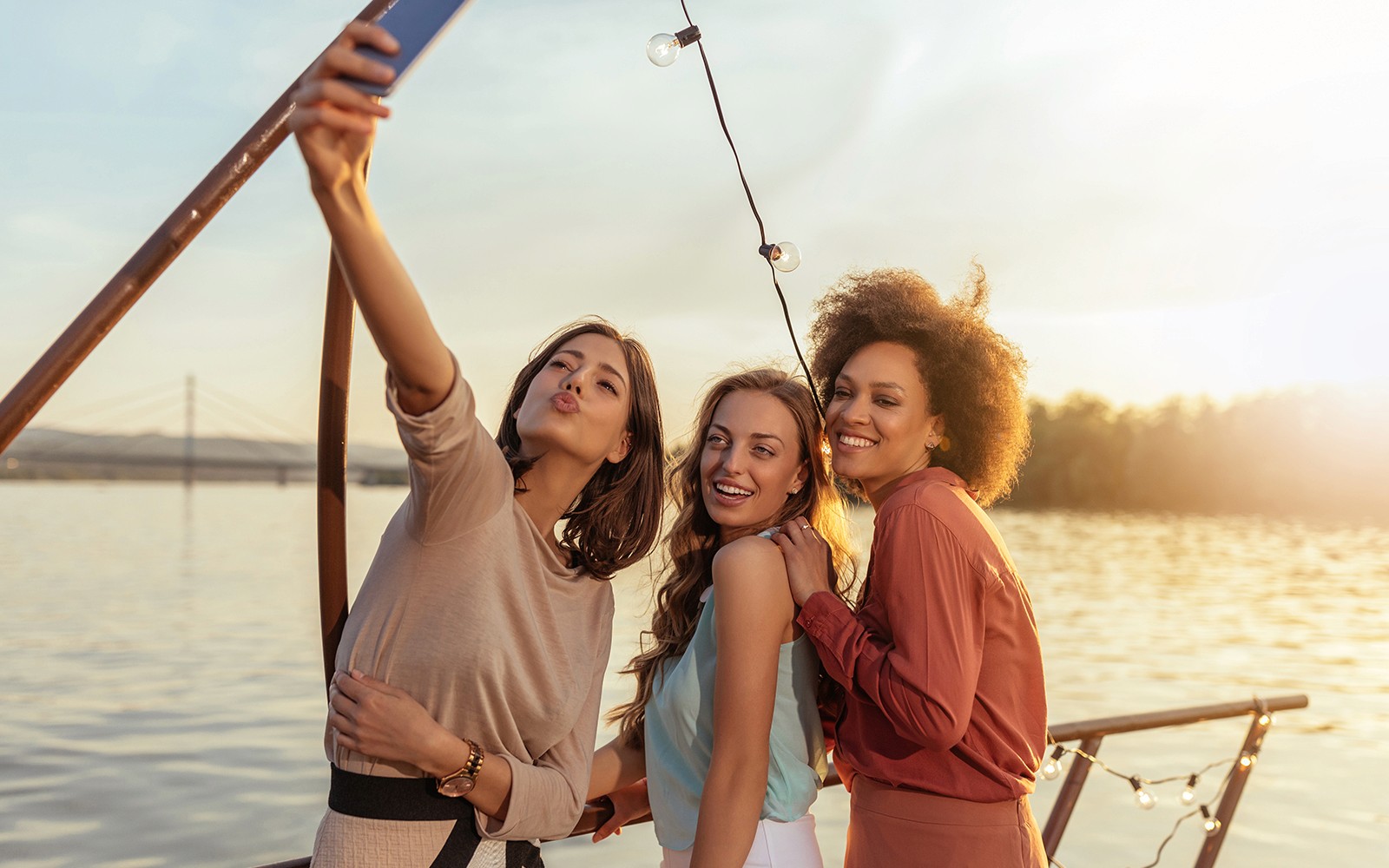 Turistas a tirar uma selfie num cruzeiro festivo no Rio Douro ao pôr do sol.