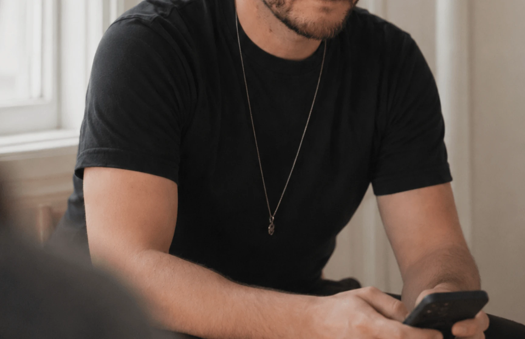 Mann mit schwarzem Tshirt scrollt auf dem Handy