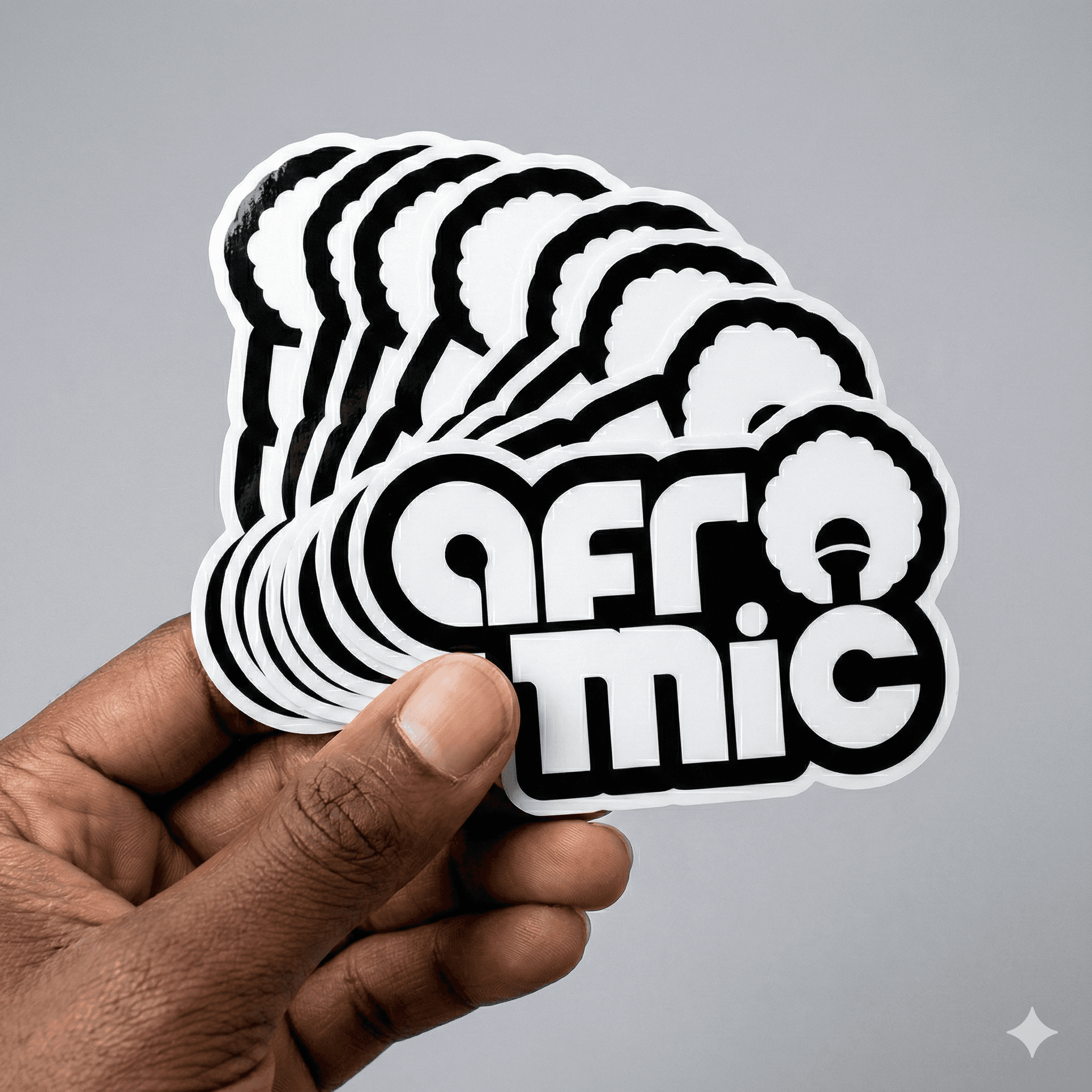 A hand holding a stack of die-cut Afromic logo stickers.