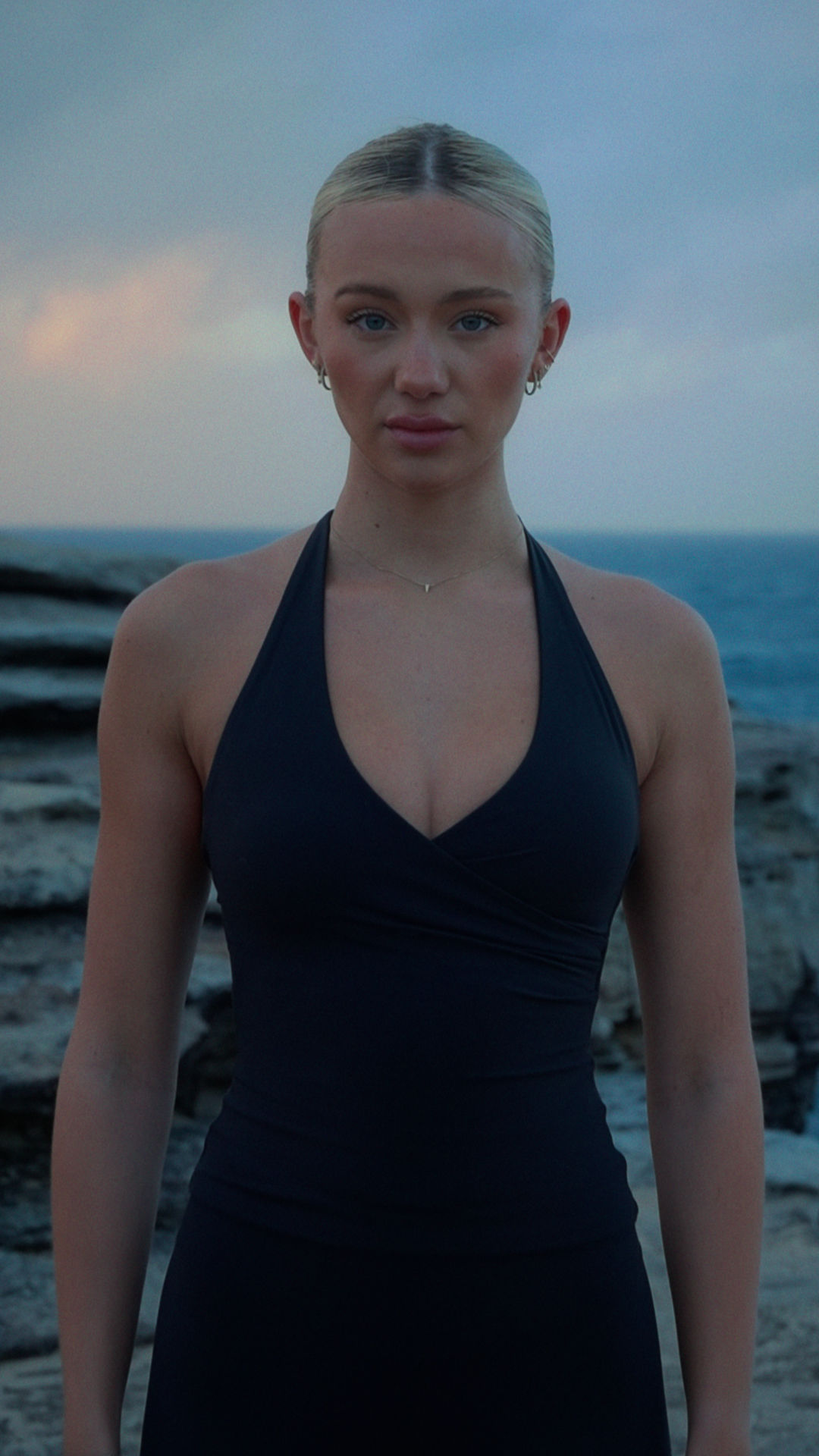 Girl staring down the camera on the edge of the cliff