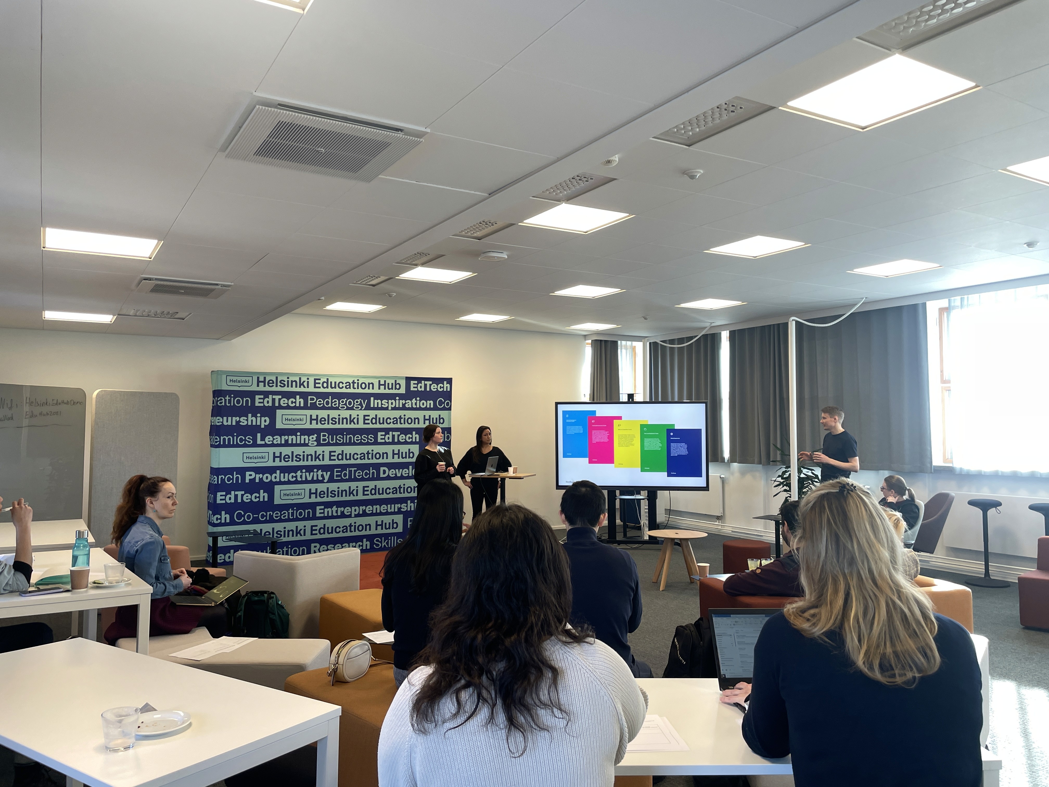 Black and white image of people working at a table with laptops, showing hands gesturing during discussion of digital content displayed on screens, with fabrica® logo in the corner.