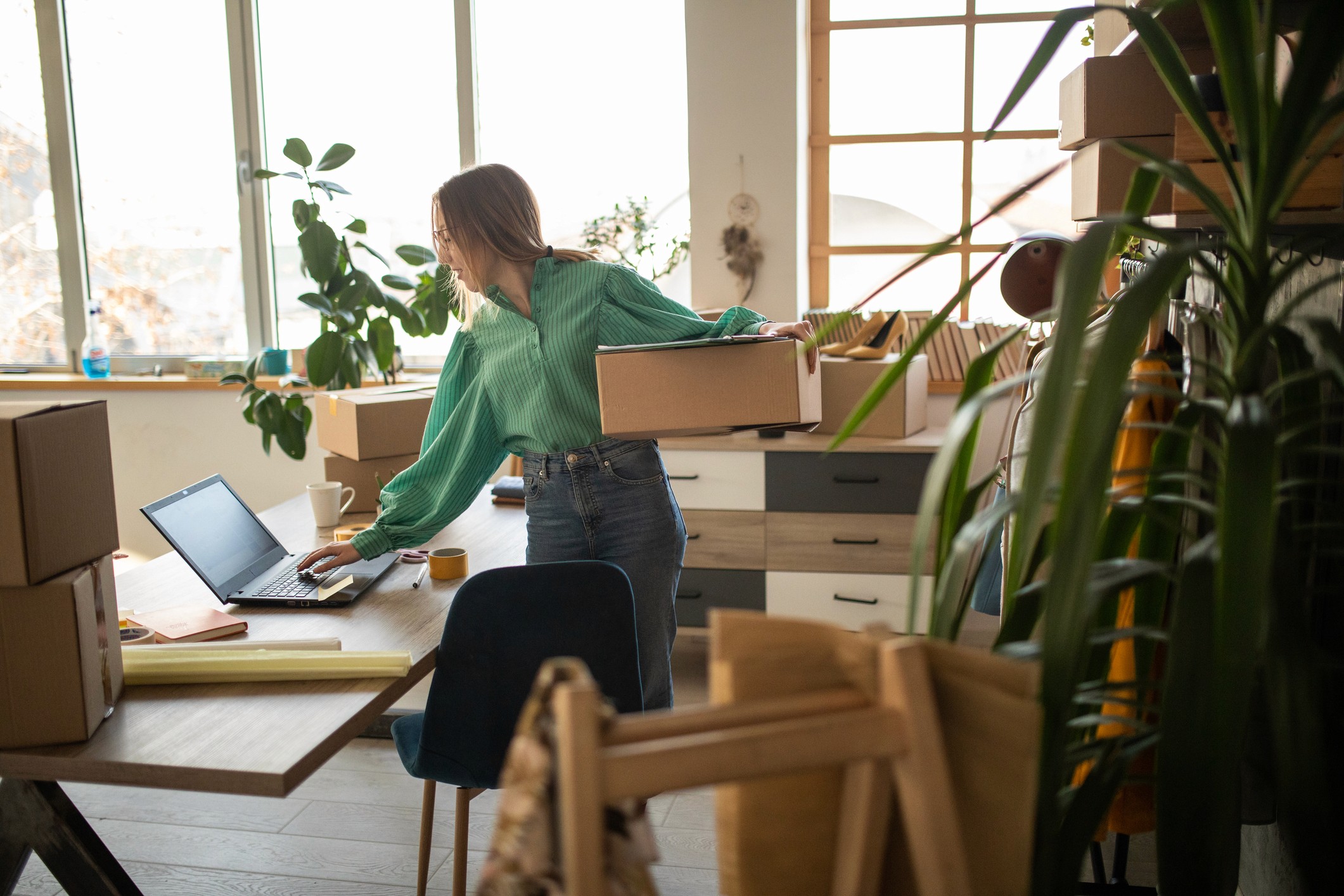 A woman holding a package types a question to the AI Analyst on her laptop.