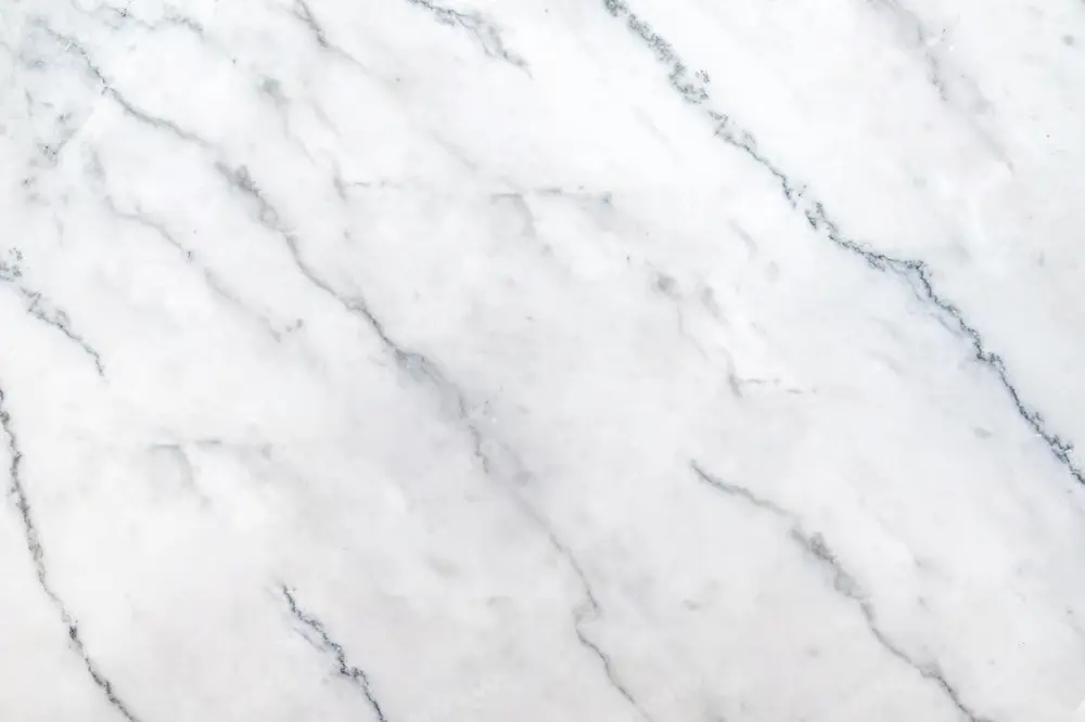 A pristine slab of Greek White marble featuring a brilliant white background and subtle grey veins.