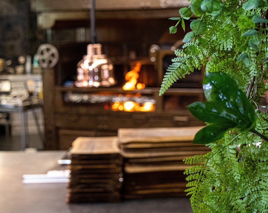 Atmosféra v restauraci s pohledem na pec a naskládané dřevo