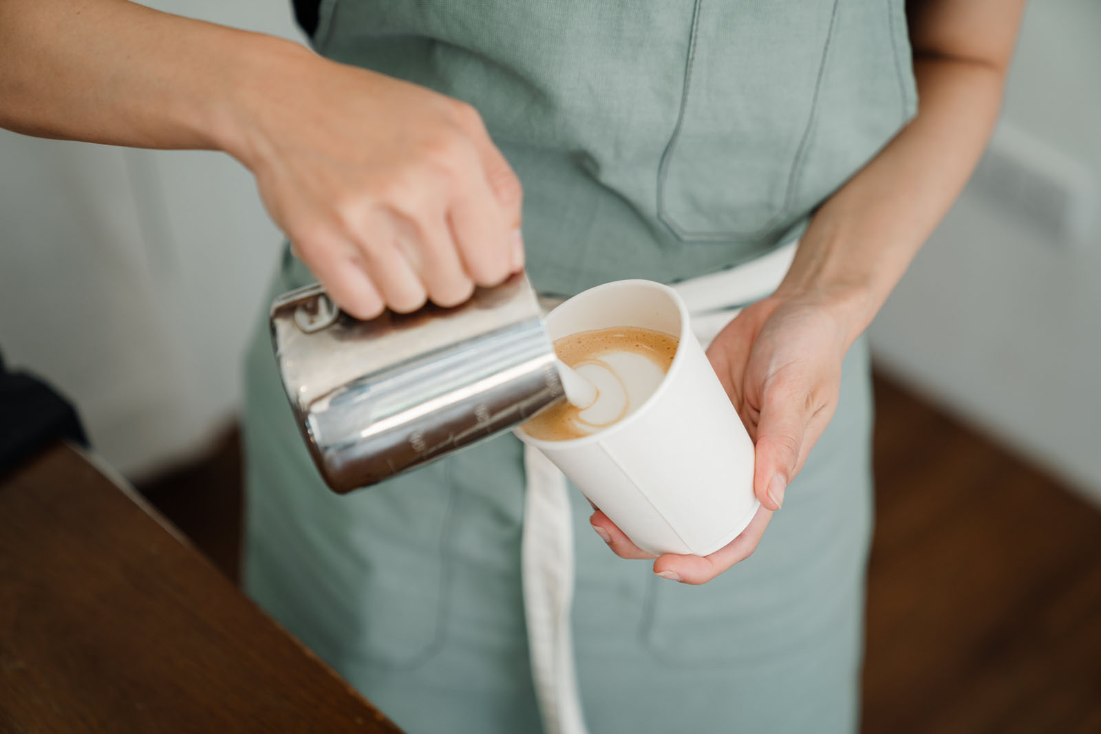 Barista pouring frothed milk into coffee cup