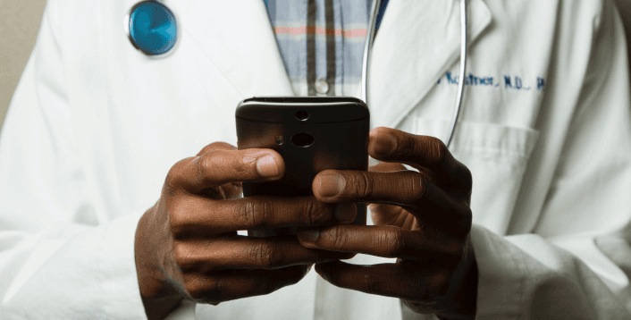 Doctor in lab coat using smartphone.