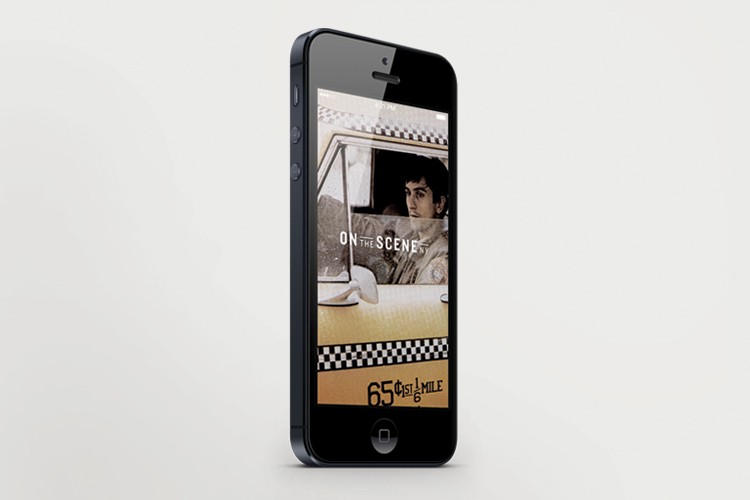 A black iPhone is positioned vertically on a white background, displaying a video on its screen. The video shows a man with dark hair looking out of a car window. The screen also displays text that reads “ON THE SCENE” at the top and “65¢1/6 MILE” at the bottom. The phone’s front buttons are visible on the left side.