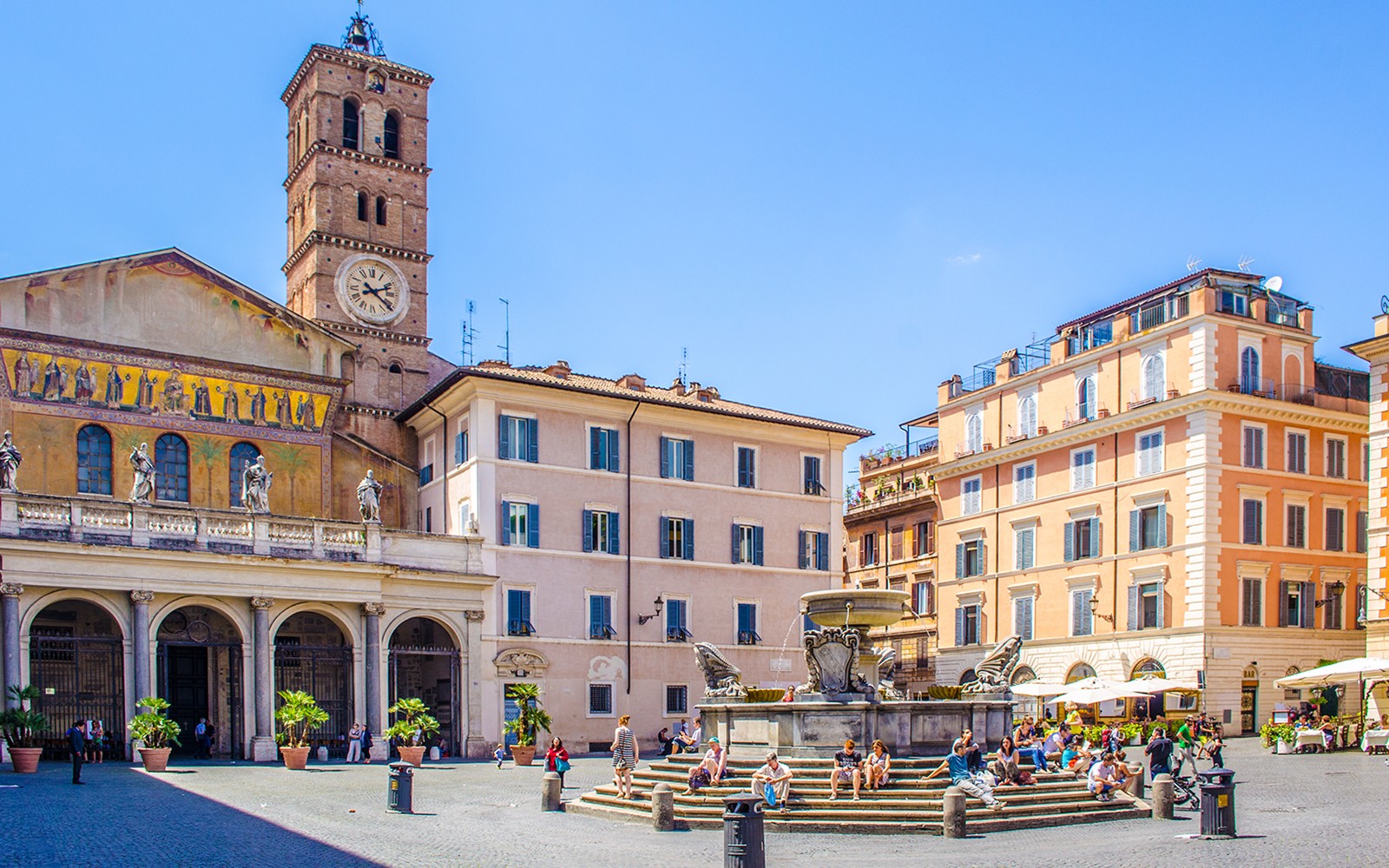 人们漫步在罗马特拉斯提弗列的圣玛利亚广场，靠近大教堂和喷泉。