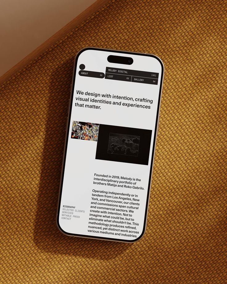 Minimalistic, modern interior design features soft white walls, geometric orange accents on block seating, and a smooth gray marble-like textured wall with a subtle plaque, creating a clean, contemporary atmosphere.