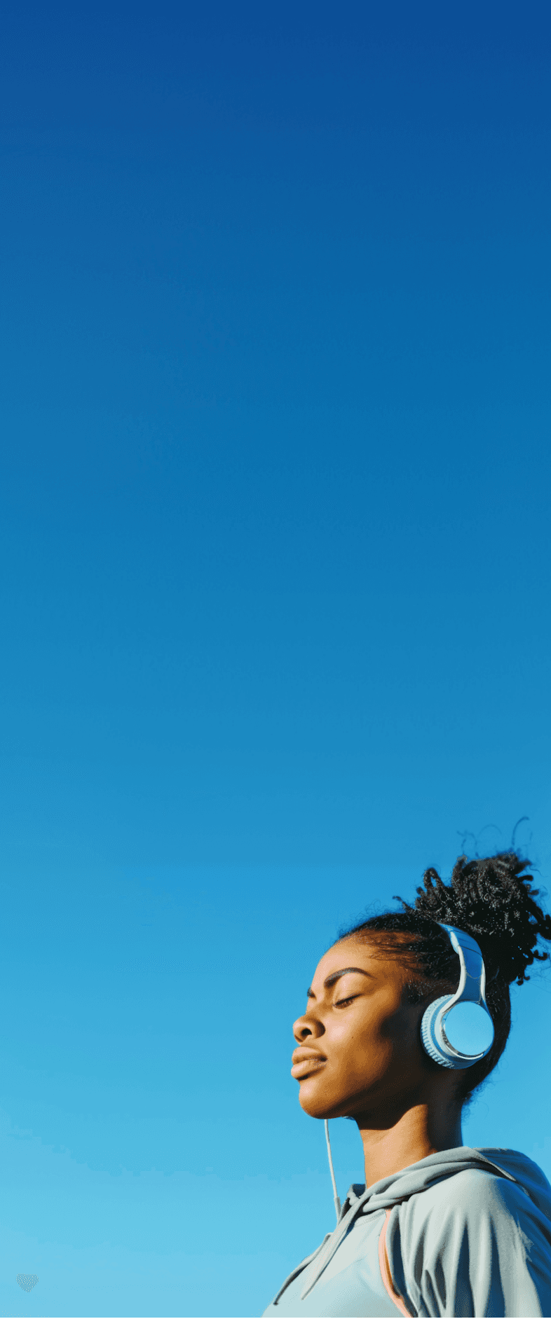 Fan listening to music with headphones under a clear blue sky