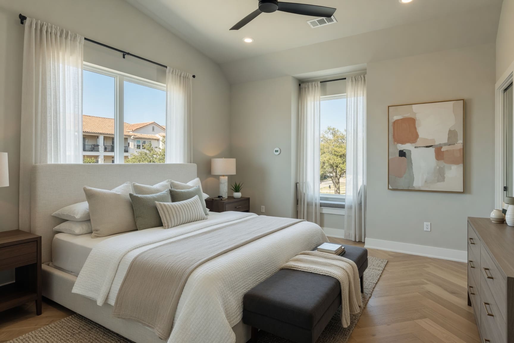 Bright primary bedroom with large windows and neutral tones