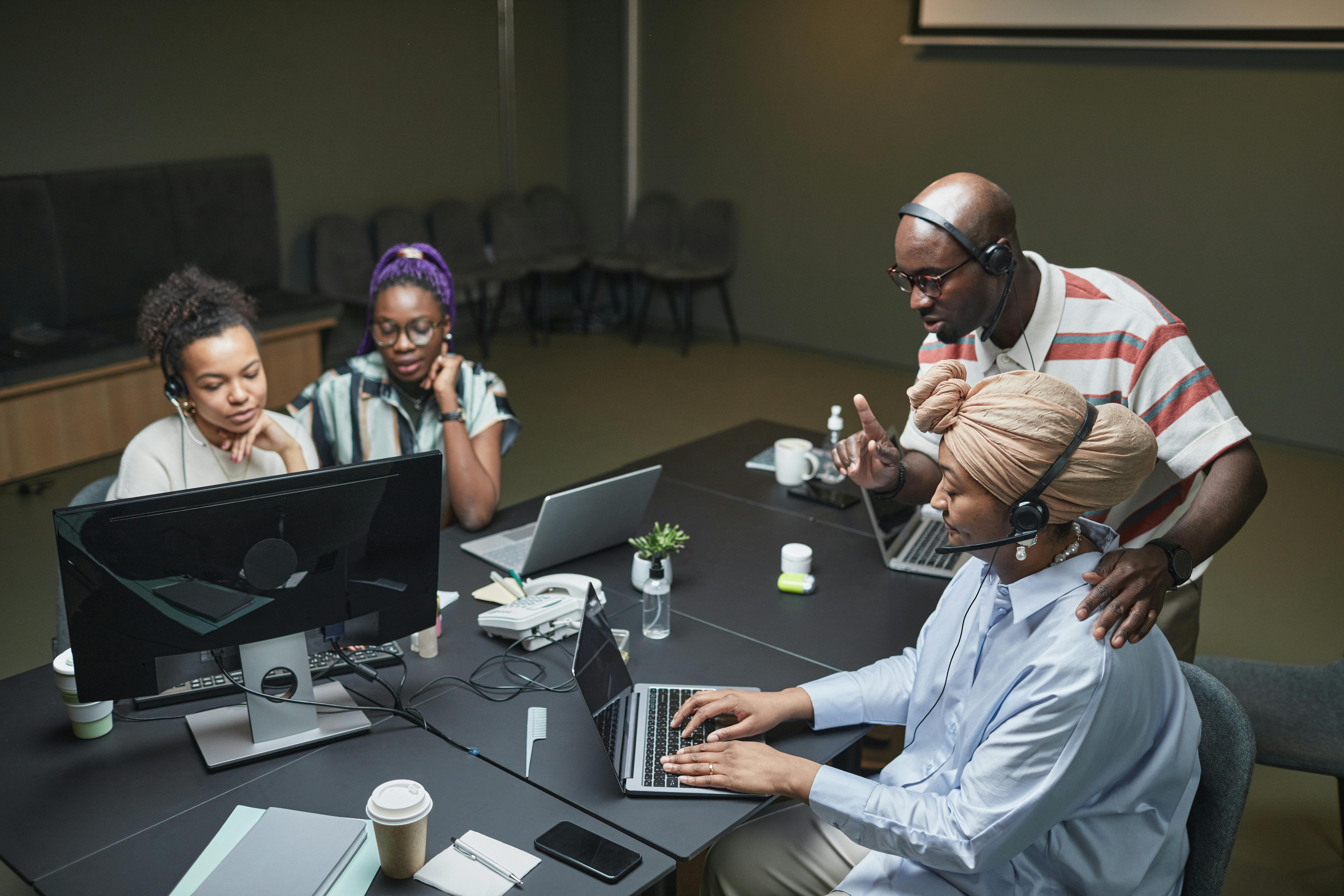 4 people working on their computers together in a work setting