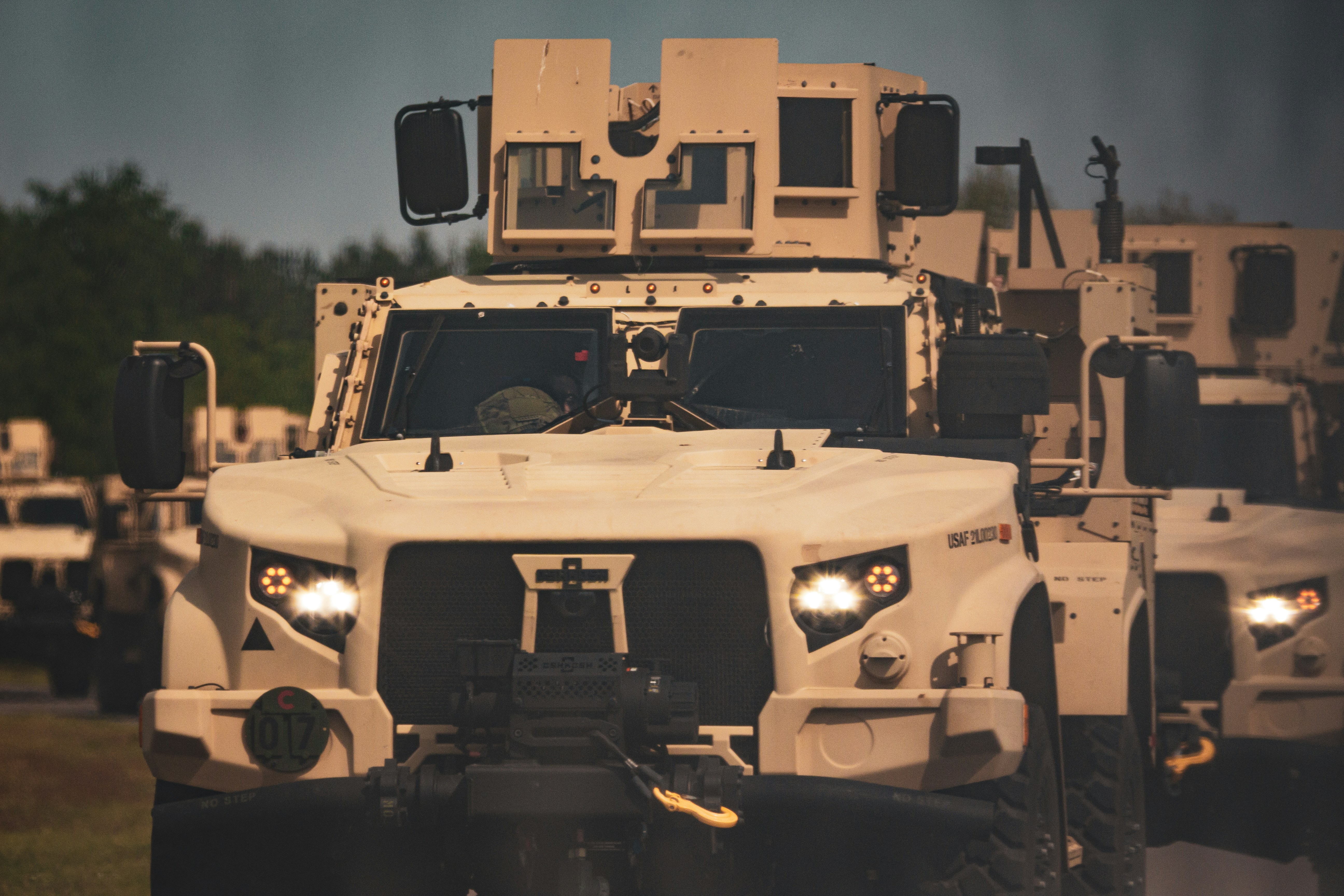 A group of military vehicles driving down a road