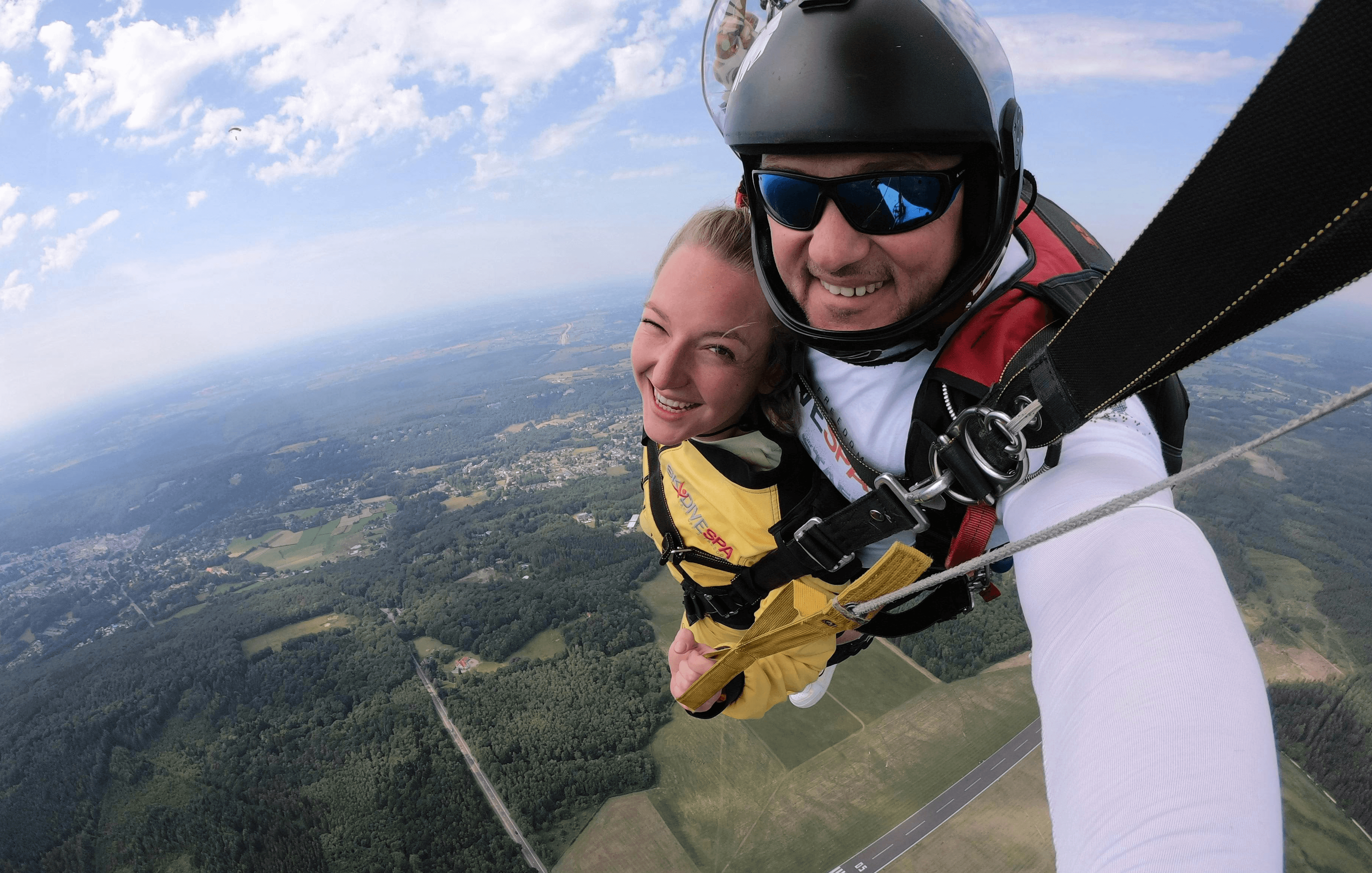 A woman and man taking a selfie as they skydive.