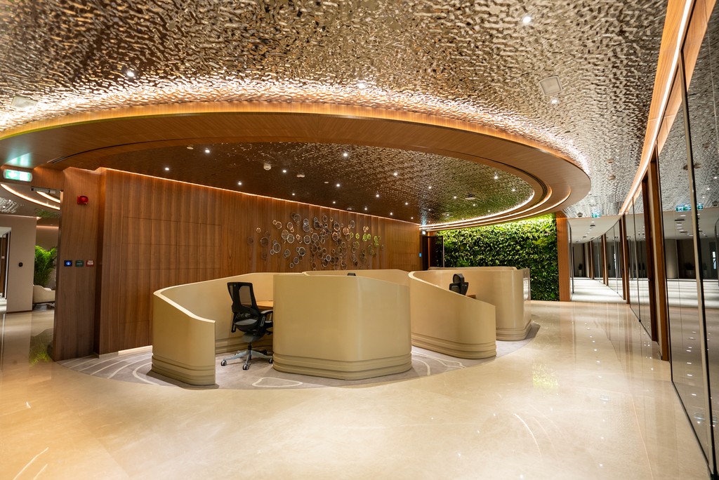 Reception area of a high-end coworking space in Abu Dhabi featuring modern design, warm wood tones, and a living green wall.