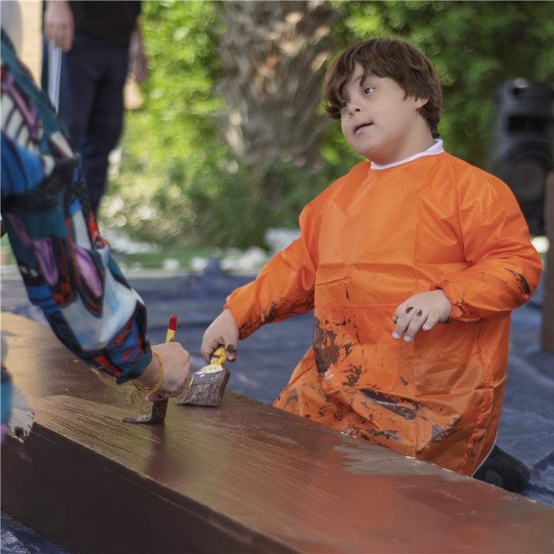 Una persona con una camiseta negra y pantalones de color claro está de pie en la cima rocosa de una montaña al atardecer, sosteniendo una cámara frente a su cara para tomar una foto. Un mar de nubes se extiende detrás de ellos, iluminado por la luz dorada del sol poniente.