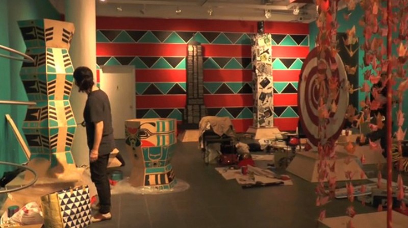 A photo of a person checking the Tall Tales A Modern Totem Pole exhibition