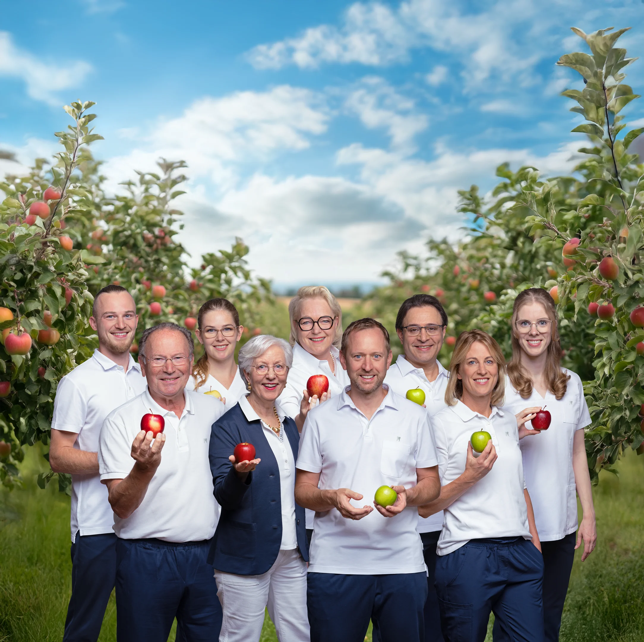 Gruppenfoto des Zahnarzt-Teams in einem Feld mit Apfelbäumen