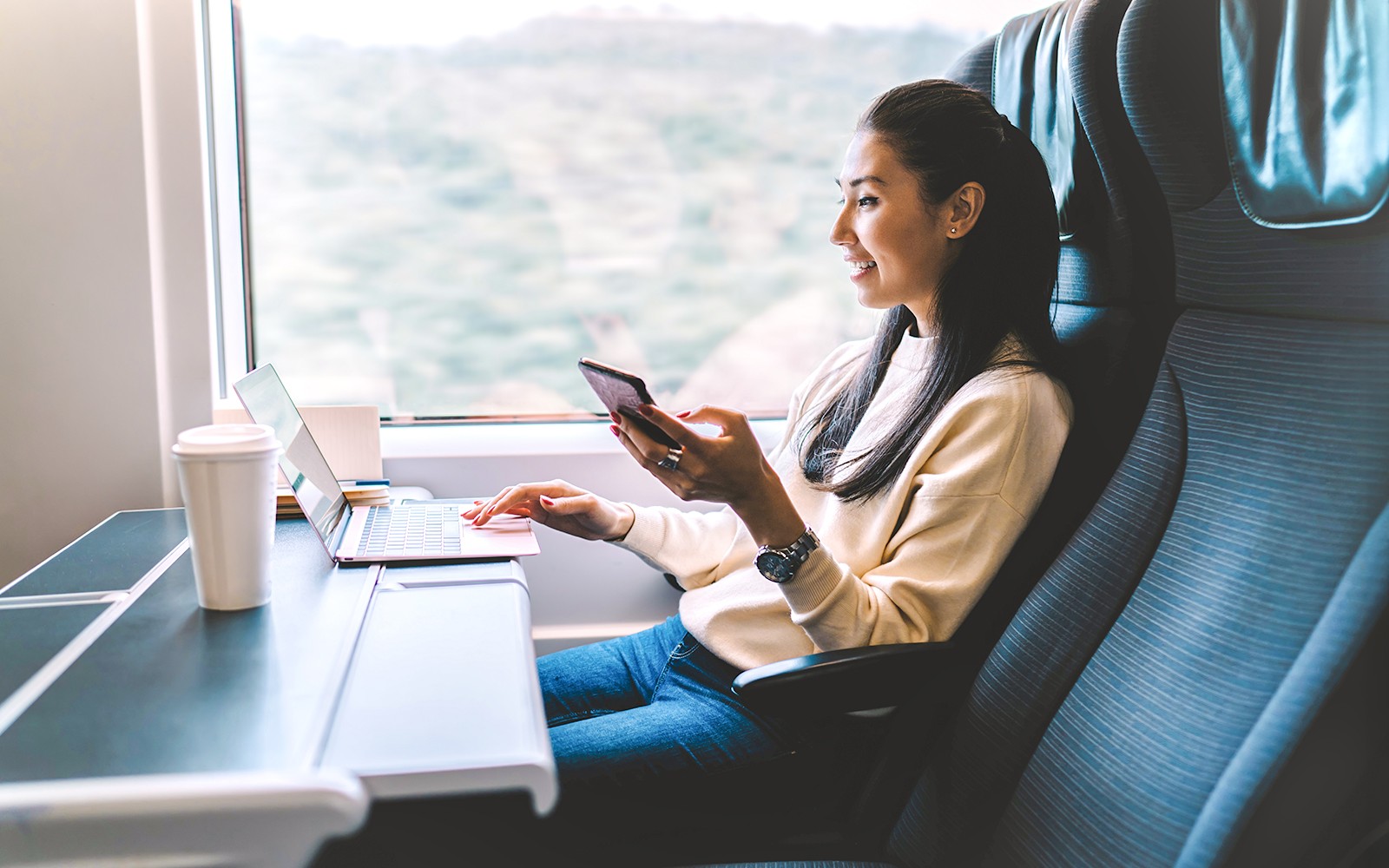 年轻女性正在欧洲之星列车旅程中使用智能手机。