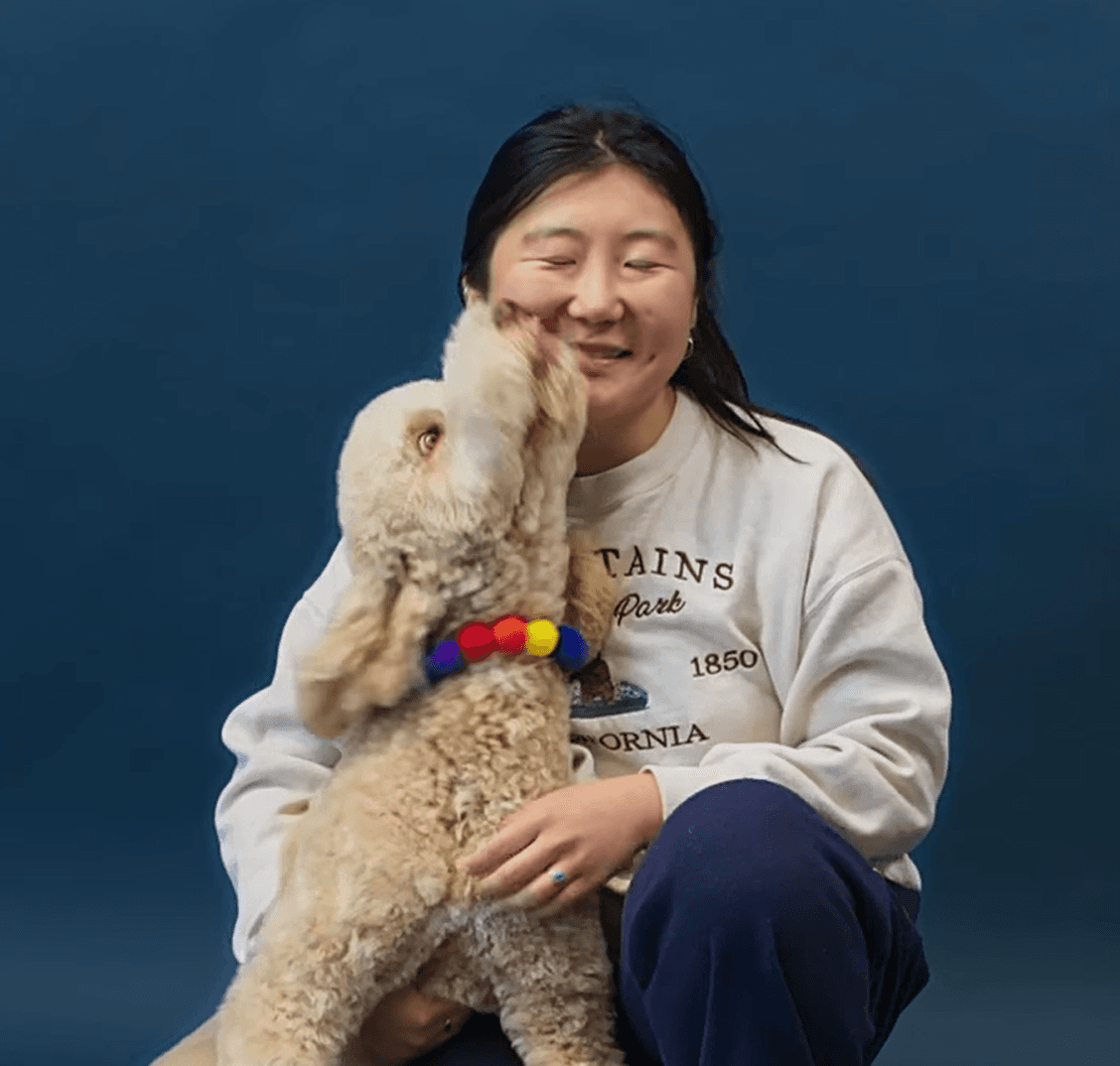 Candid photo of a young woman holding a fluffy puppy and laughing to reflect connection, playfulness, and premium pet care.