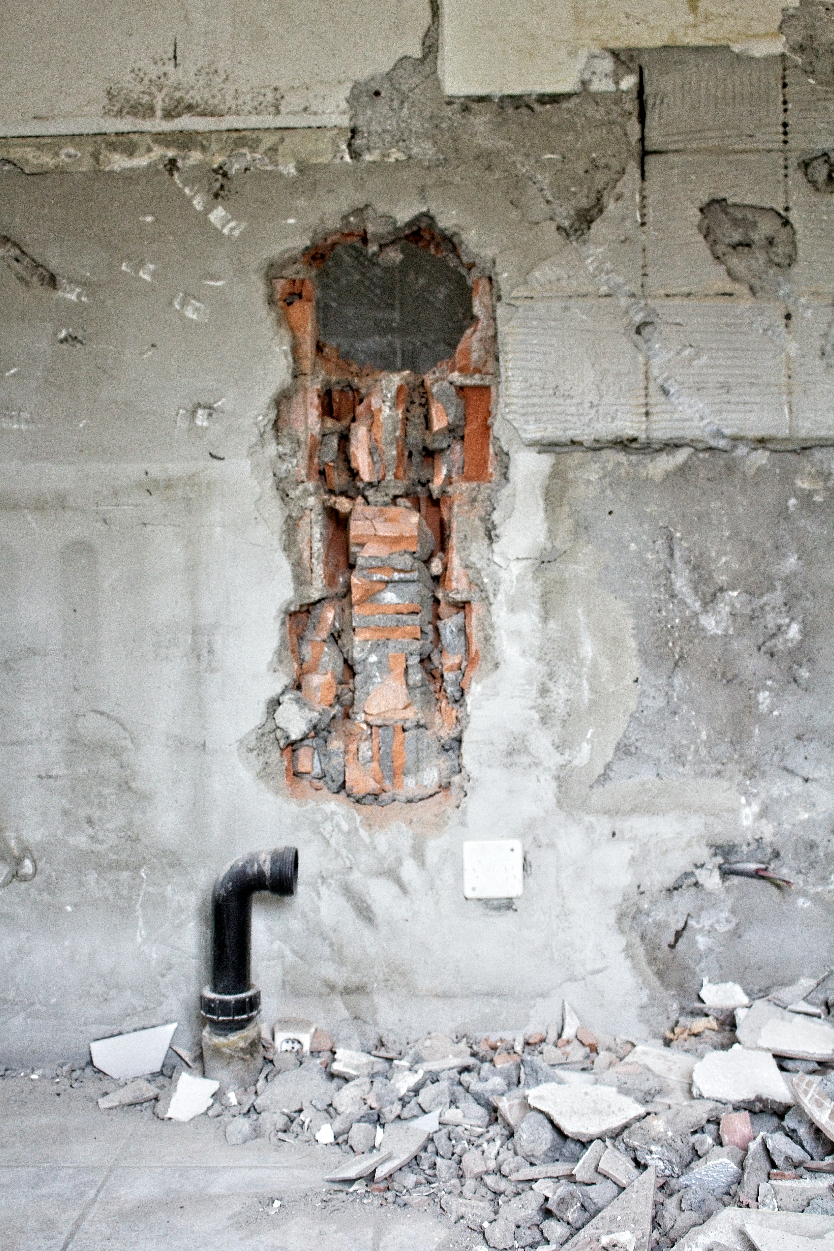a fire hydrant sitting in front of a wall with a hole in it