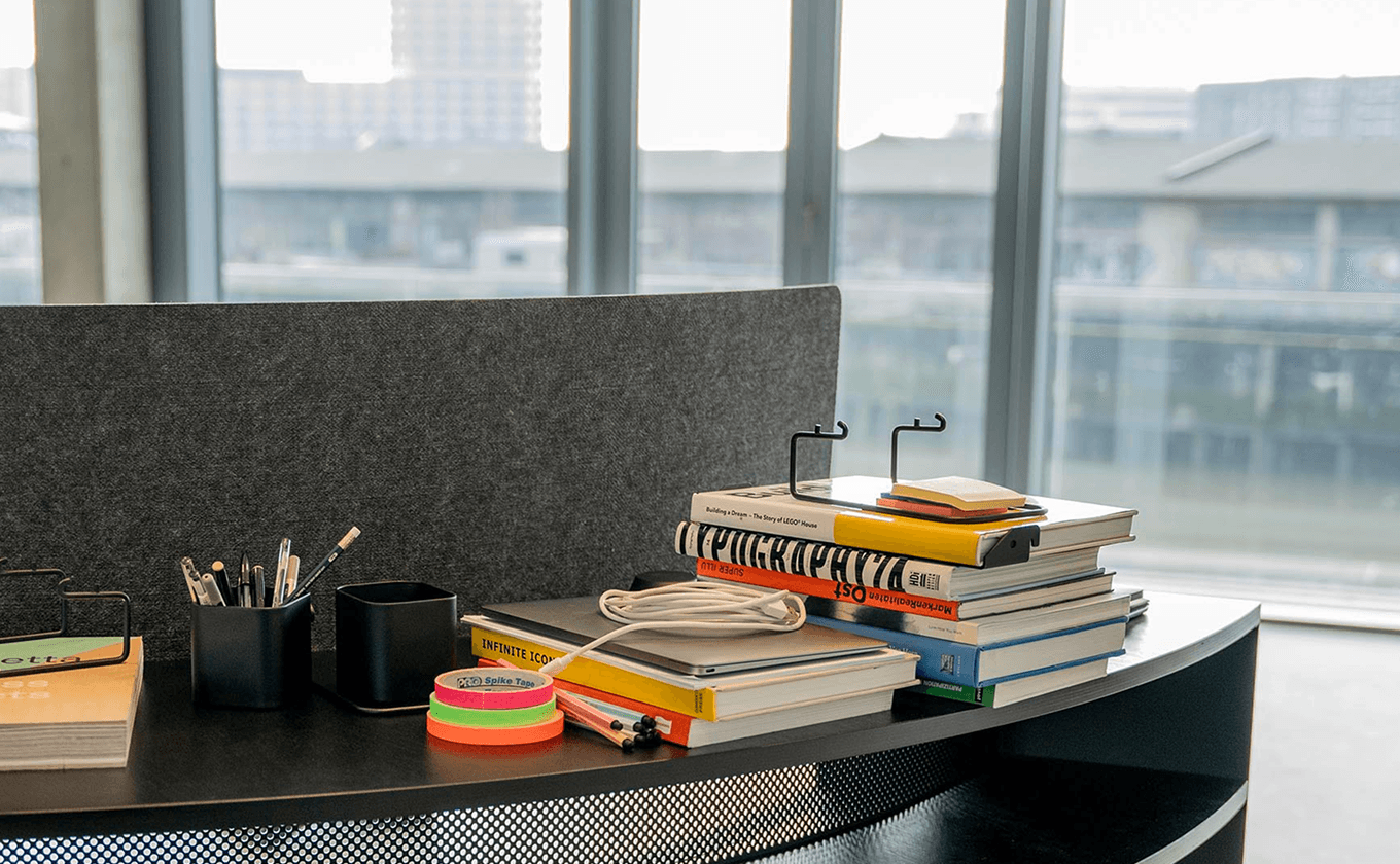 SCOPE Steh-Arbeitsplatz an der Pultbank mit grauer Filz-Rückwand, Organizer-System und Büromaterialien im modularen Setup.