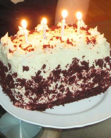 Red velvet cake with white frosting and lit birthday candles
