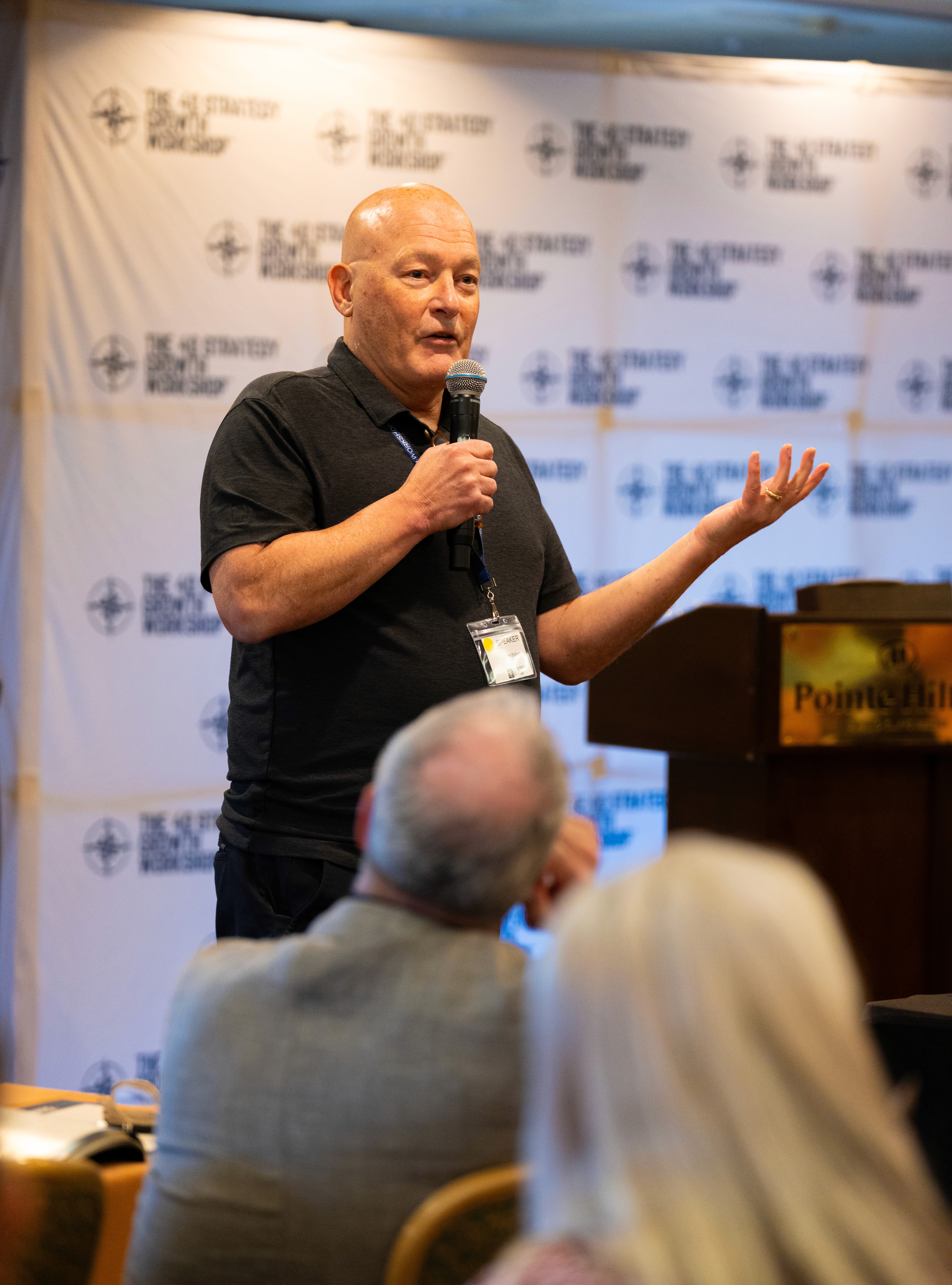 Man in a sweater smiling with arms crossed while standing by a wooden wall.