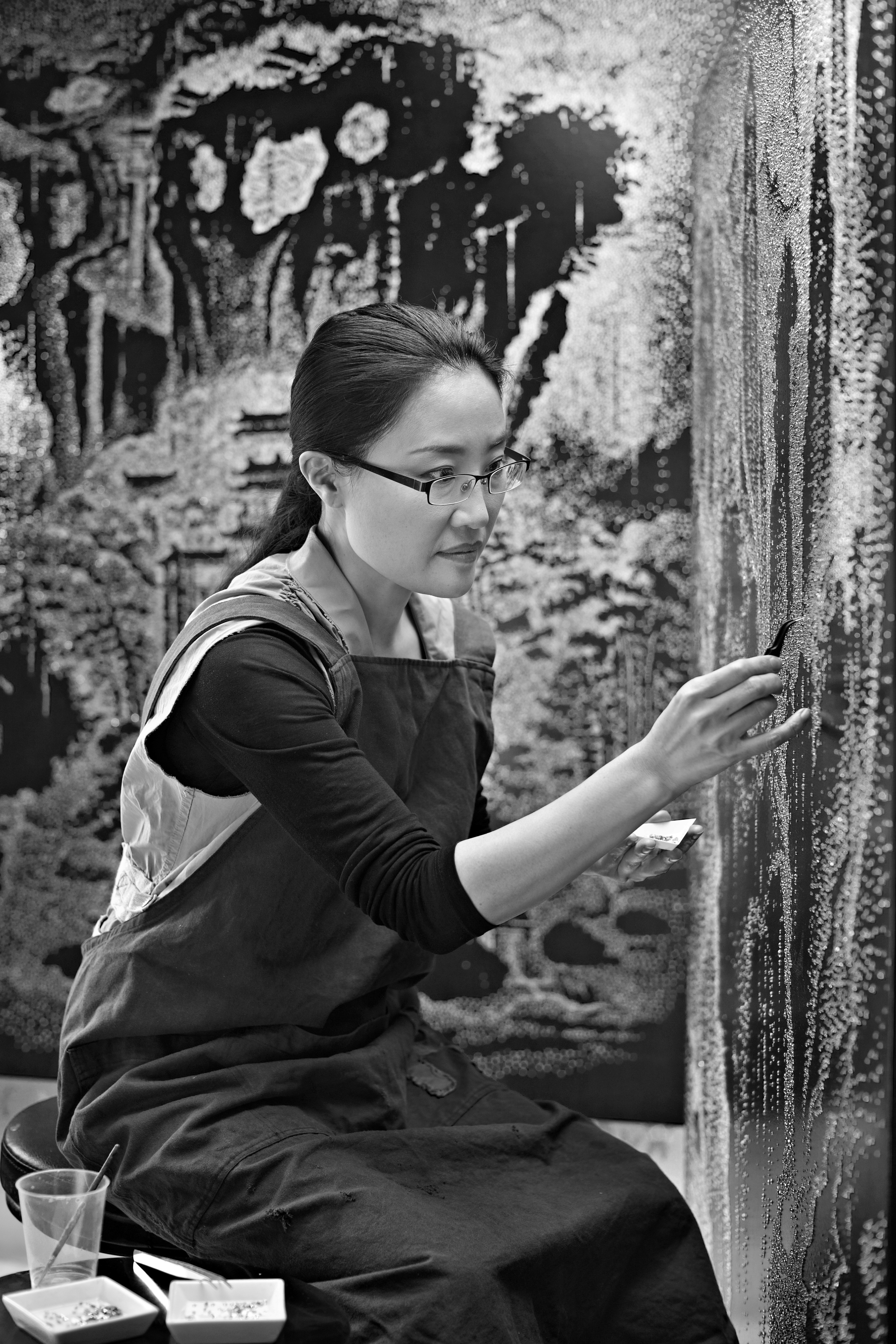 A woman observes framed black-and-white photographs in warm golden light