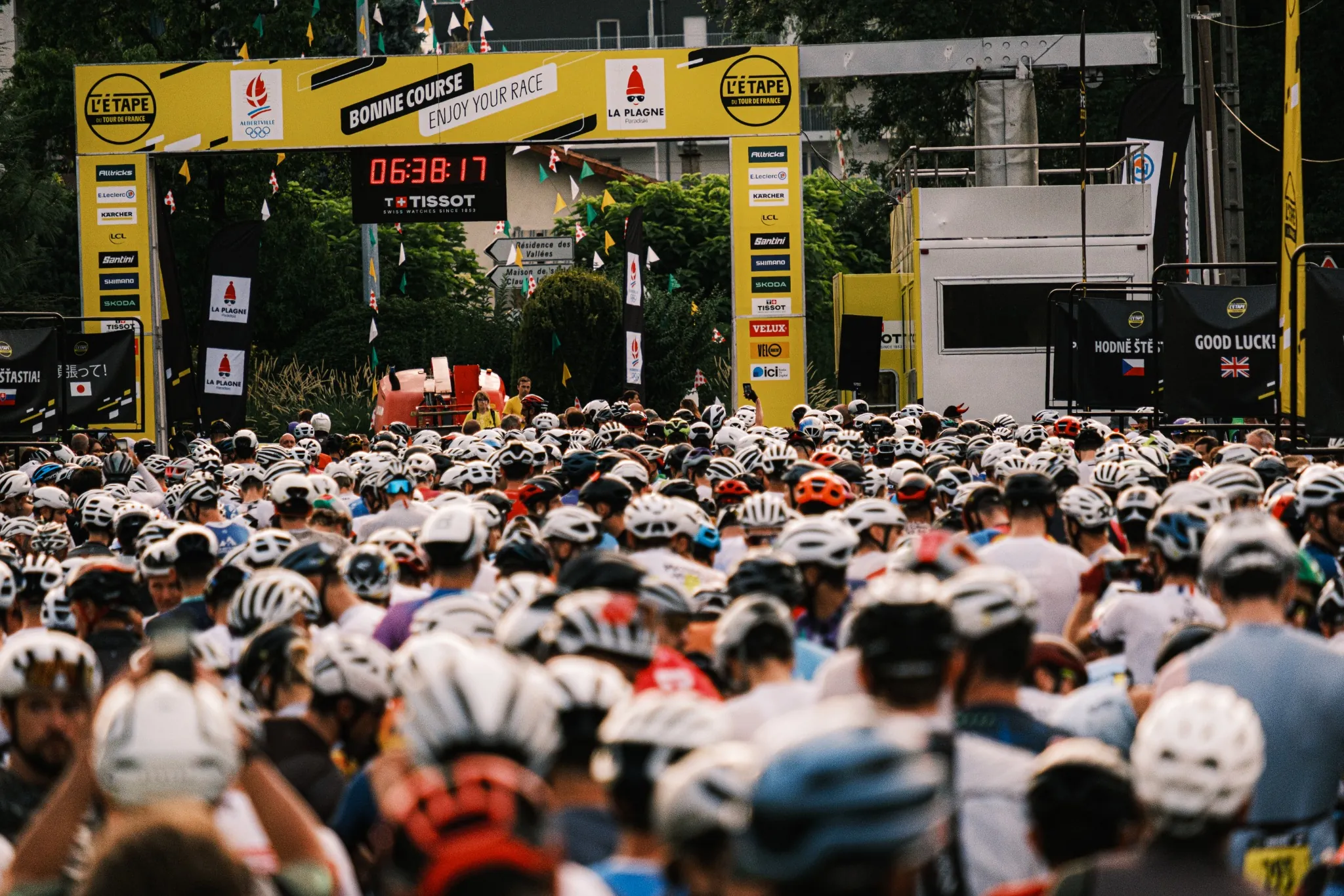 Peloton Julbo au départ de l’Étape du Tour, casques blancs et maillots violets sous la ligne de départ.