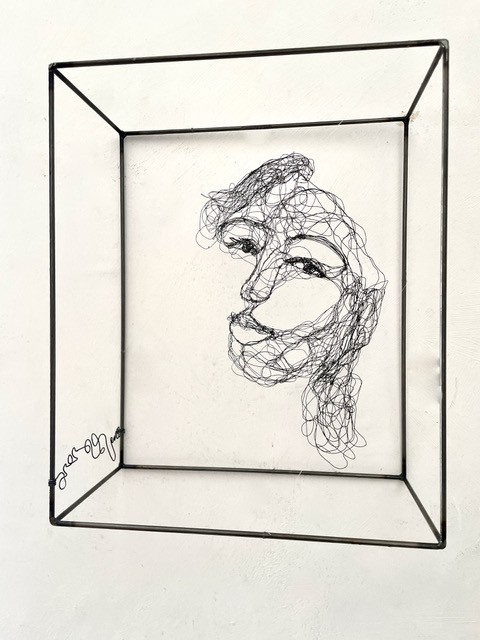 Sculpture en fil de fer représentant le visage d'une femme dans un cadre en fil de fer, vue détaillée de face